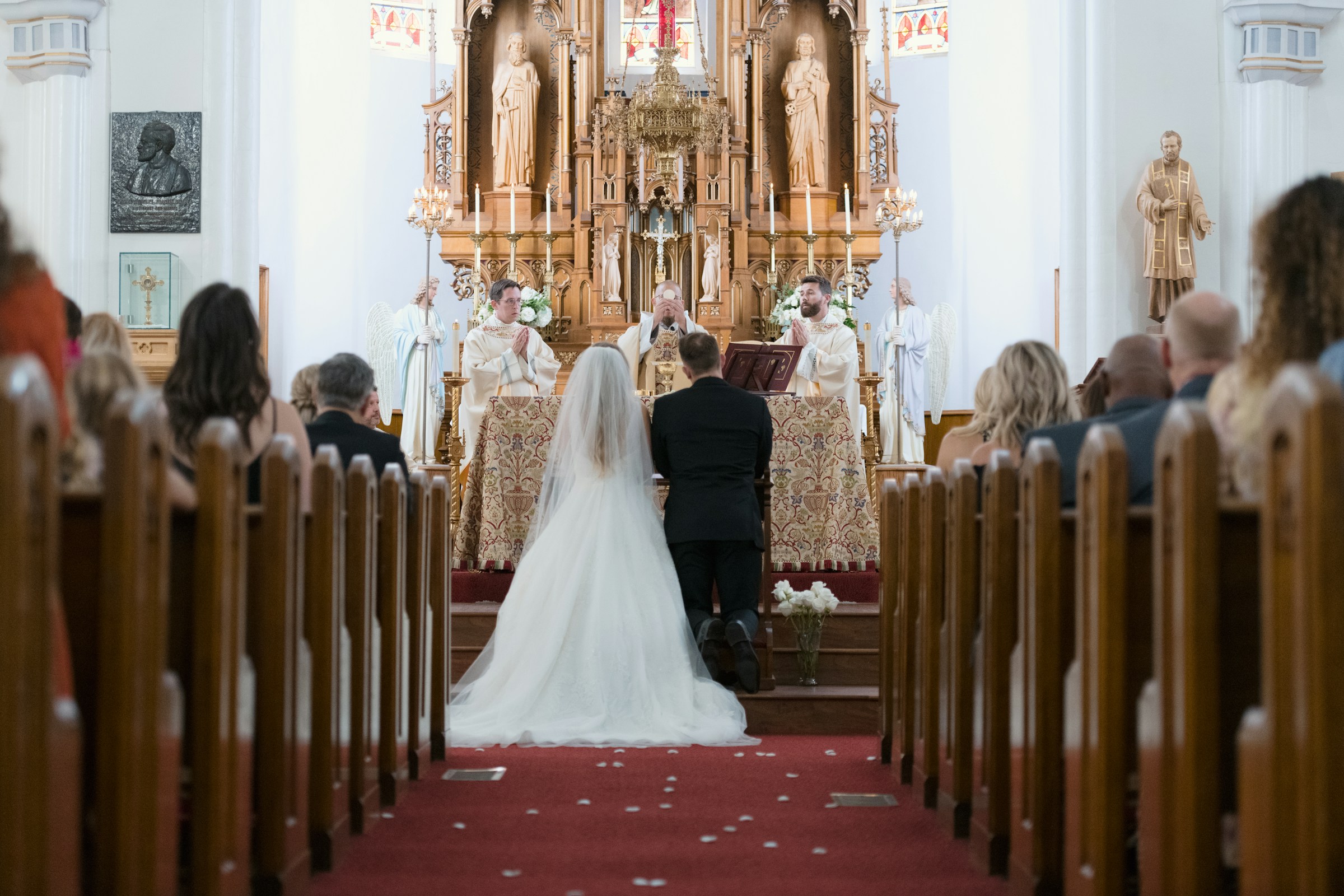 Una pareja de novios en el altar durante una boda por la iglesia mientras el sacerdote eleva El Santísimo Sacramento | Fuente: Unsplash