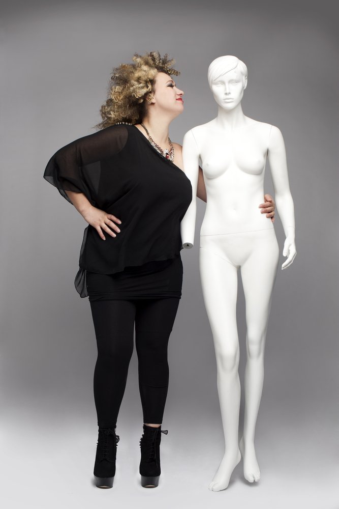 Mujer usando una blusa negra en capas y un legging negro, posando junto a un maniquí. | Foto: Shutterstock