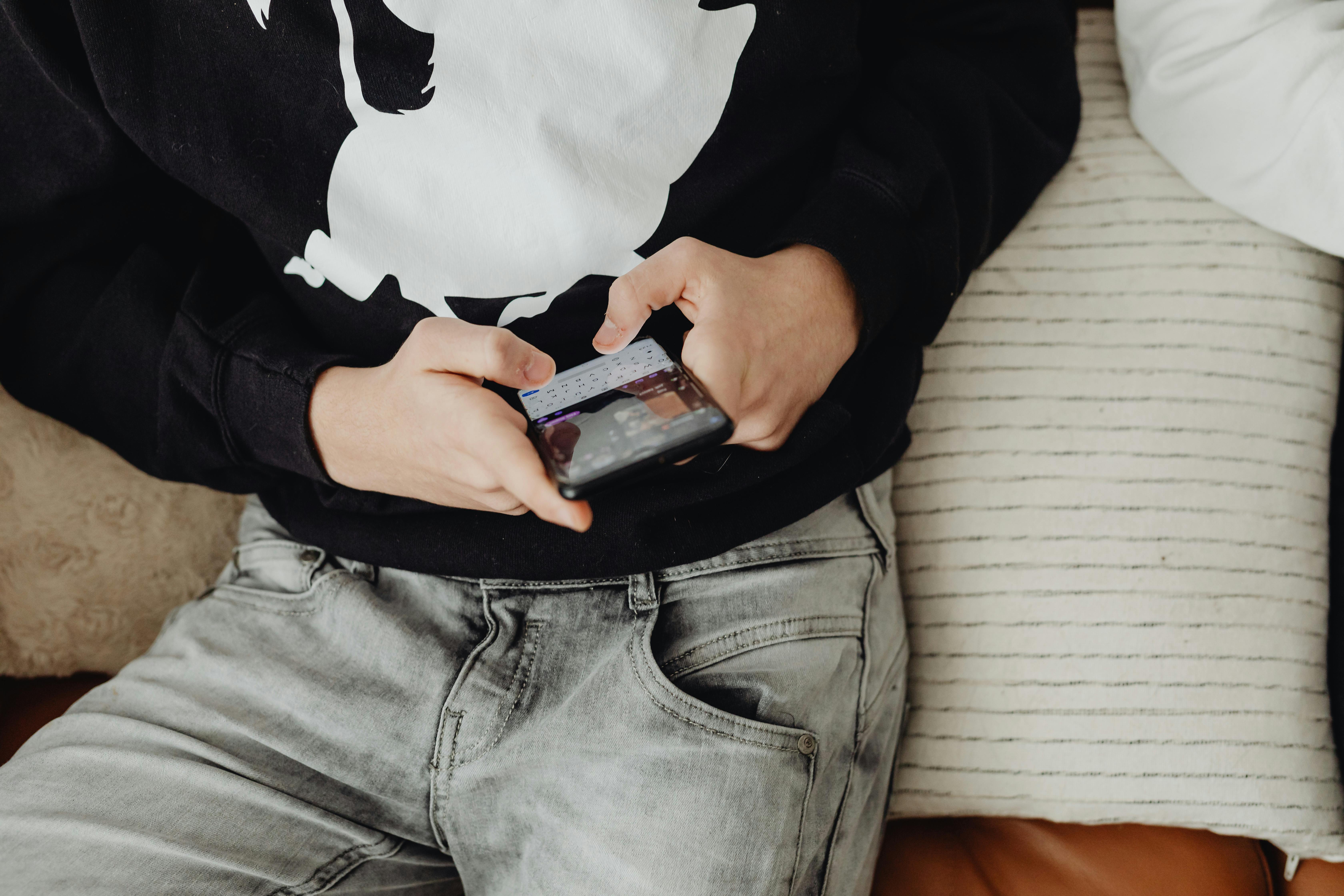 Un niño usando su teléfono mientras está sentado | Foto: Pexels