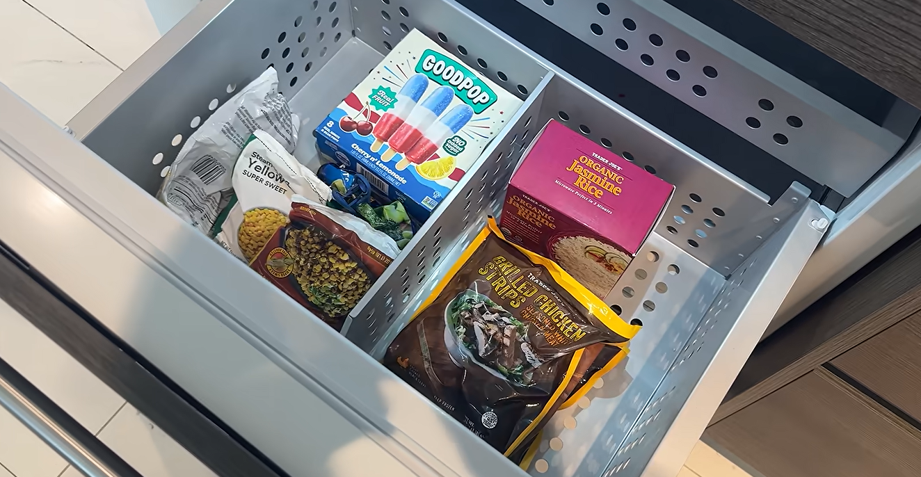 En el congelador hay comida congelada y otros productos de alimentación que aparecen en el vlog de Kai Trump de agosto de 2026. Su amiga Emma le llevó comida después de que Trump dijera que apenas había comido en tres días porque se encontraba mal. | Fuente: YouTube/kaitrump