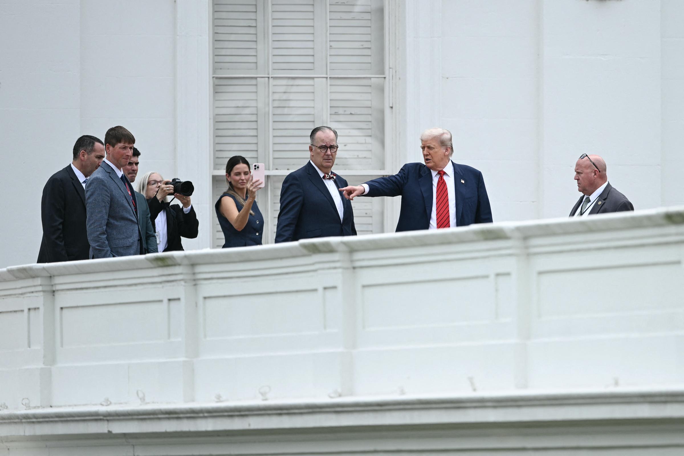 Acompañado por el arquitecto James C. McCrery y sus ayudantes, Donald Trump señala a través del techo de la Casa Blanca durante su visita a la azotea, destacando las zonas que se van a renovar mientras las cámaras captan la inusual escena.