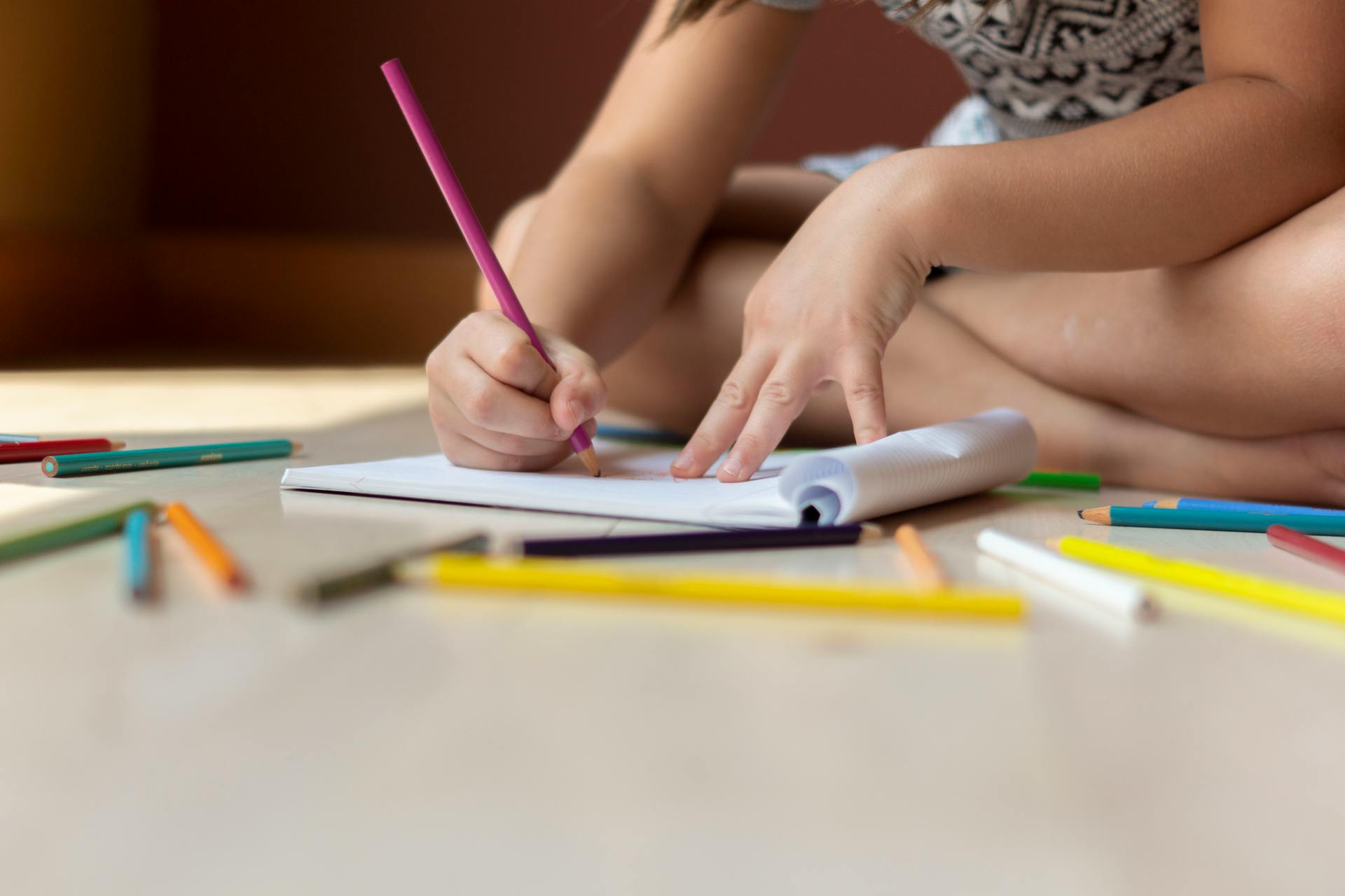 Una niña dibujando en un libro | Fuente: Pexels