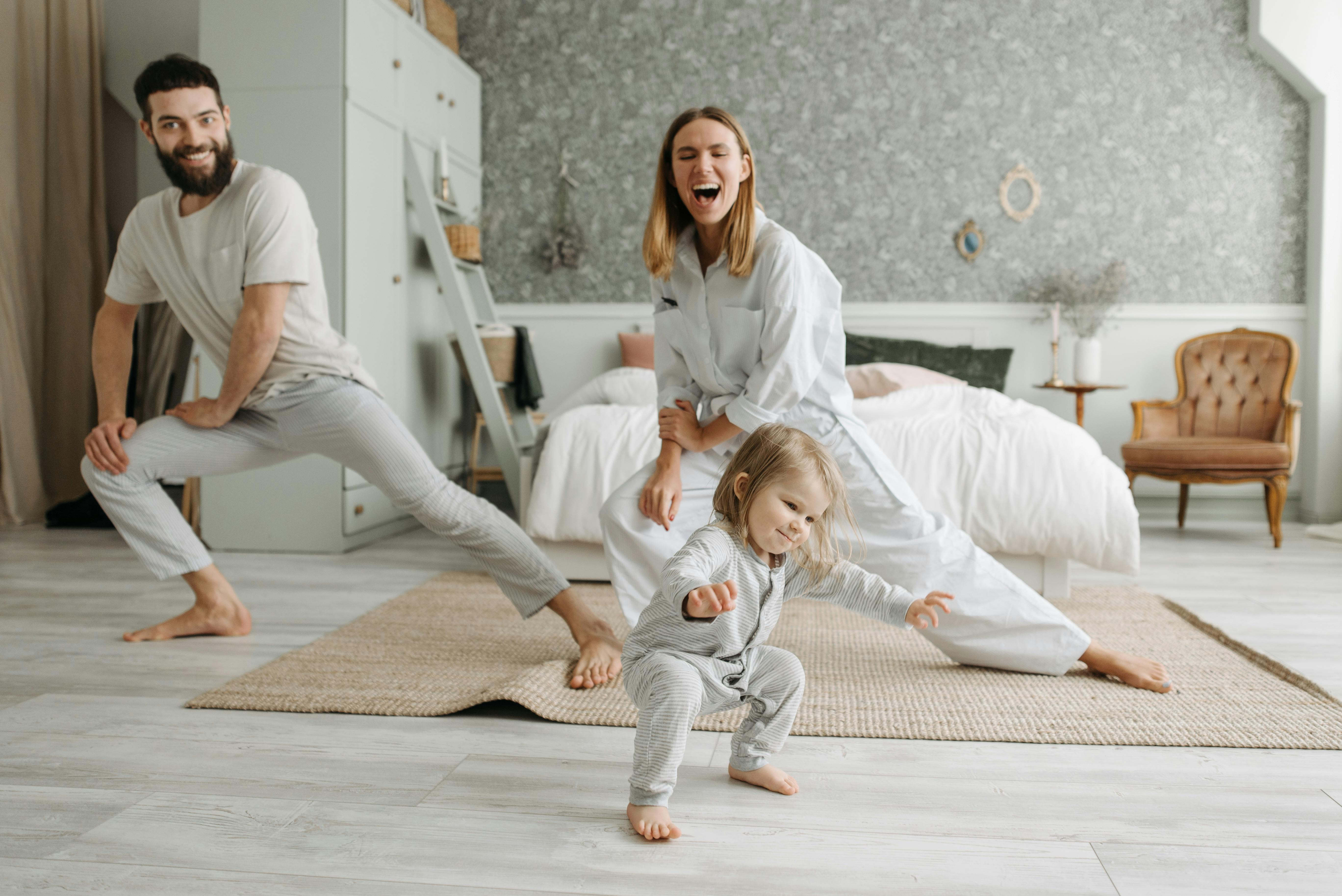 Una mamá, un papá y su hija pequeña haciendo estiramientos | Fuente: Pexels