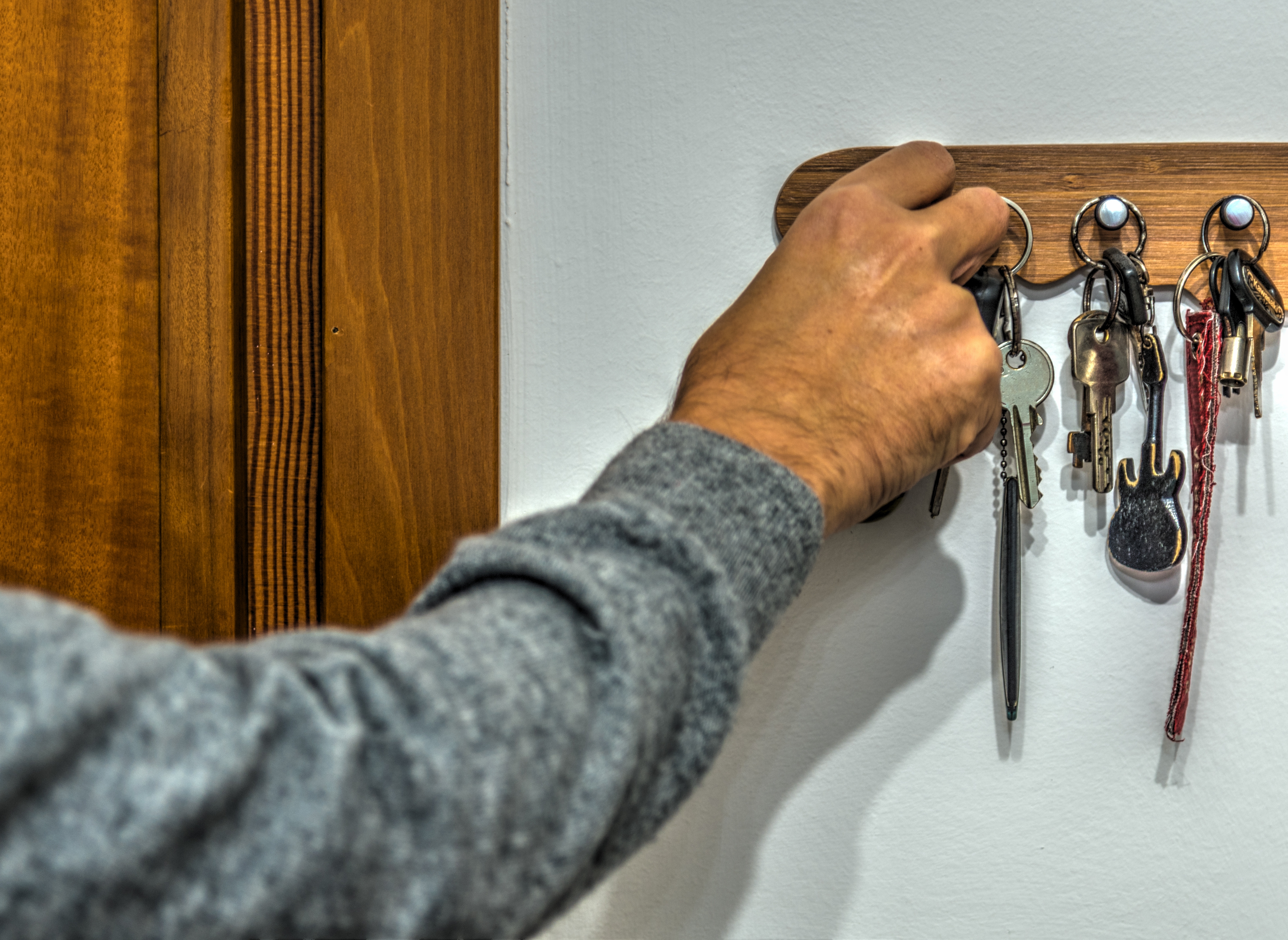 Primer plano de la mano de un hombre cogiendo una llave del llavero. | Fuente: Shutterstock