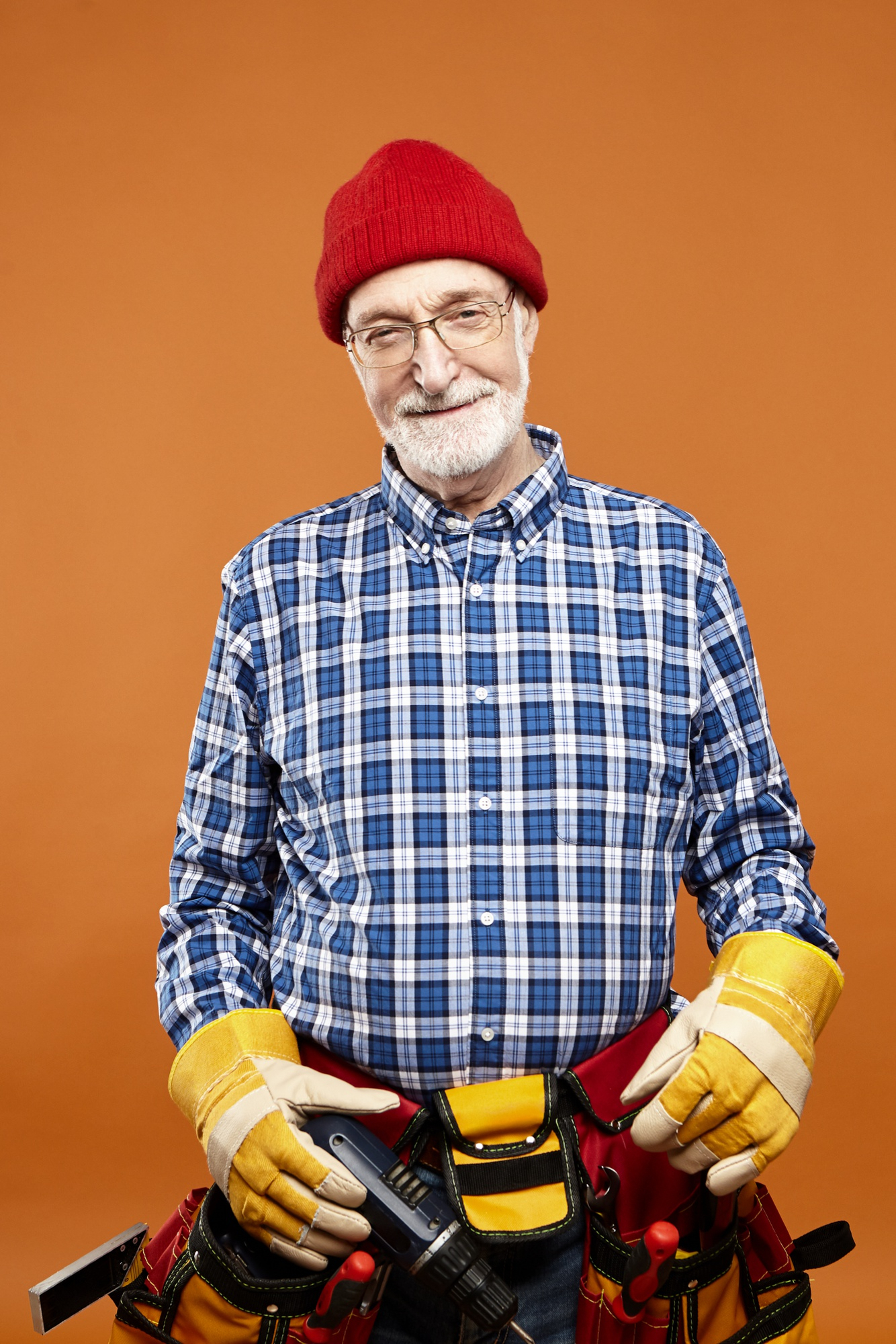 Un hombre feliz de mediana edad con un cinturón de herramientas en la mano | Fuente: Freepik