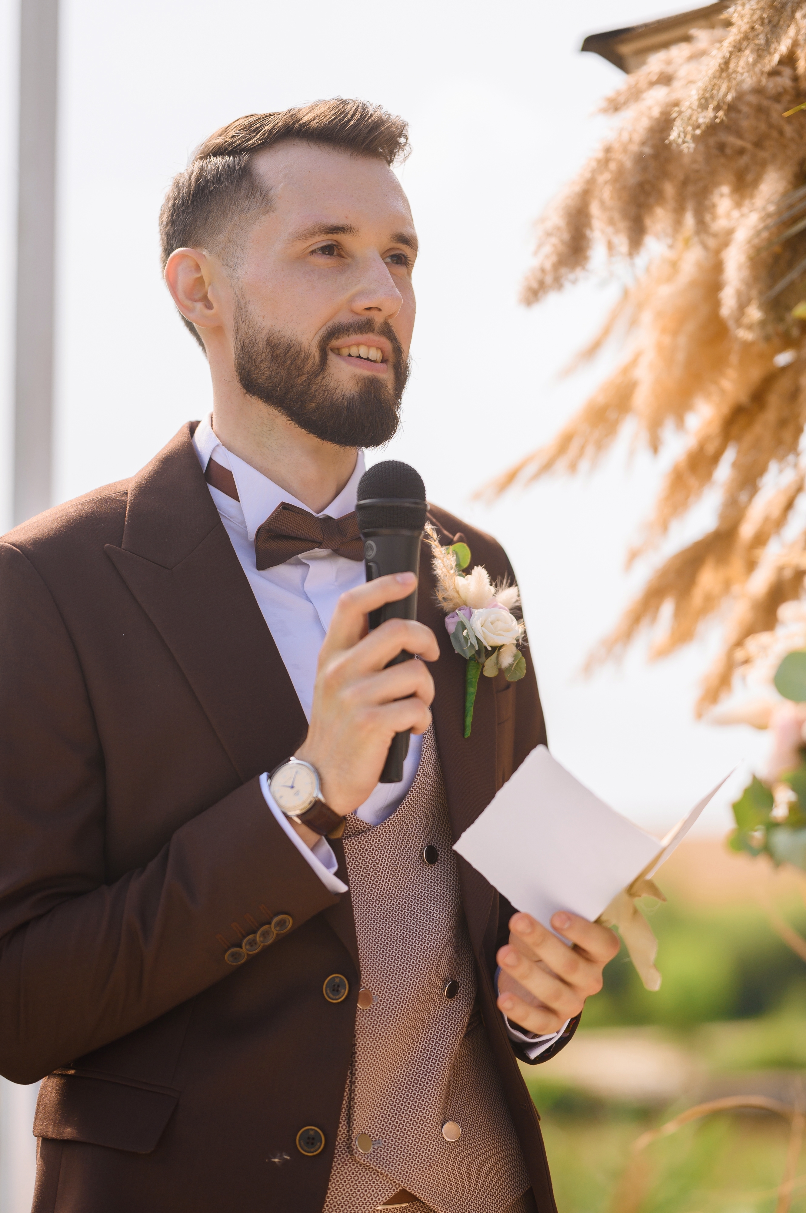 Un hombre vestido con traje marrón, con flor en el ojal y pajarita dando un discurso en una boda. | Foto: Shutterstock