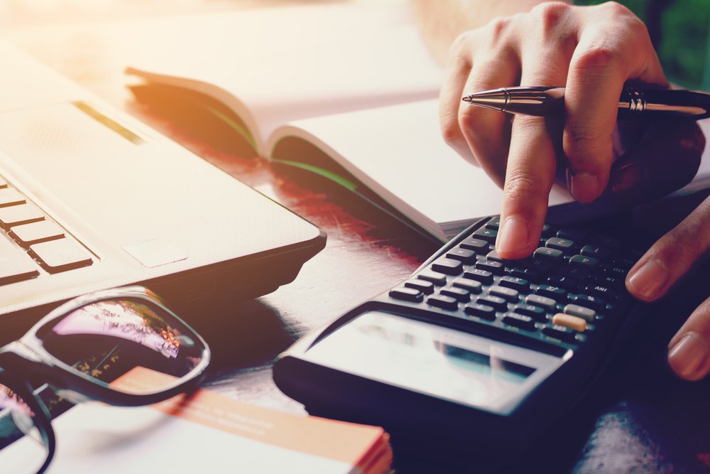 Mujer sacando cuentas y calculando gastos en la oficina. Fuente: Shutterstock