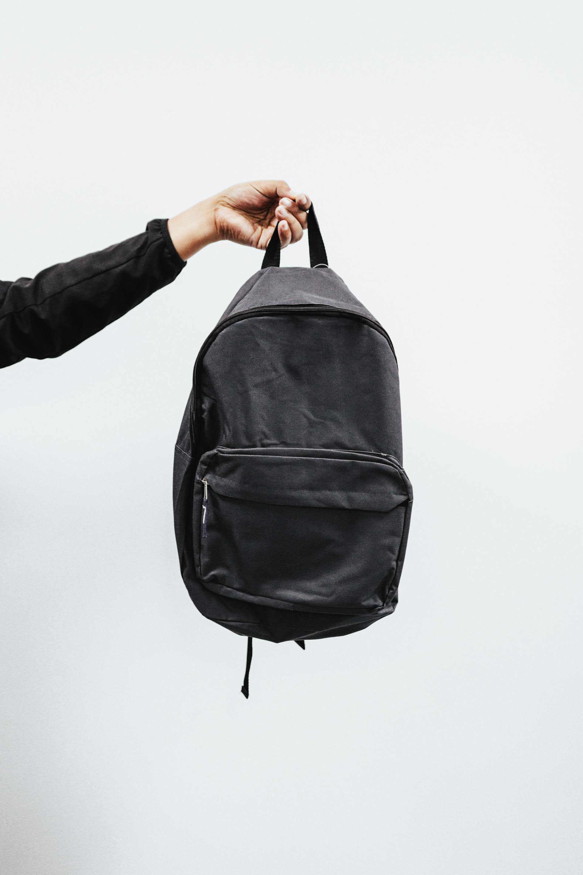 Una persona con una mochila negra en la mano | Fuente: Pexels