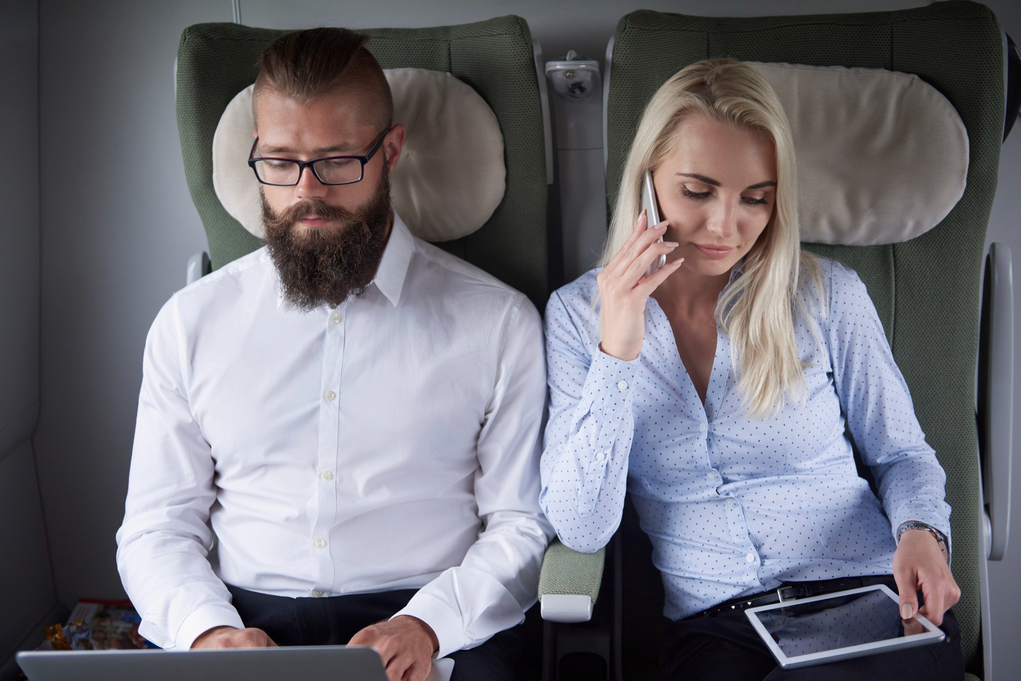 Una mujer hablando por teléfono sentada junto a un hombre en un avión | Foto: Freepik