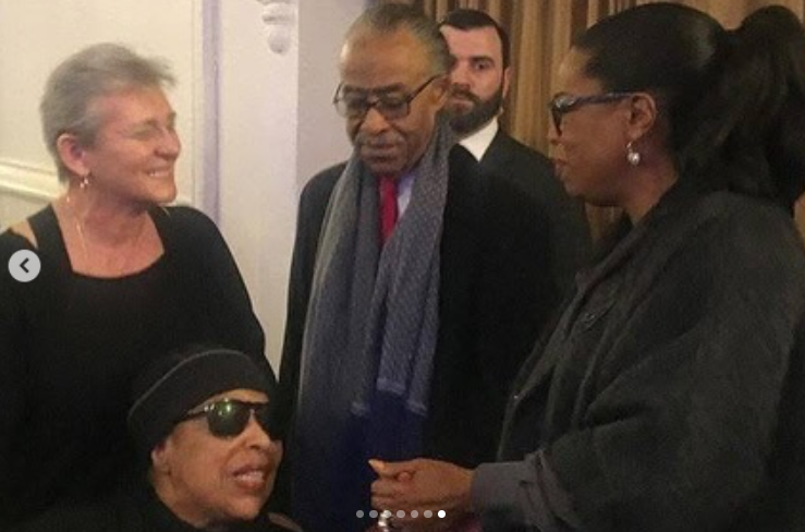 Roberta Flack, con gafas de sol y un pañuelo negro en la cabeza, compartiendo un momento con Al Sharpton y otras personas en un acto público, publicado el 24 de febrero de 2025. | Fuente: Instagram/real_sharpton