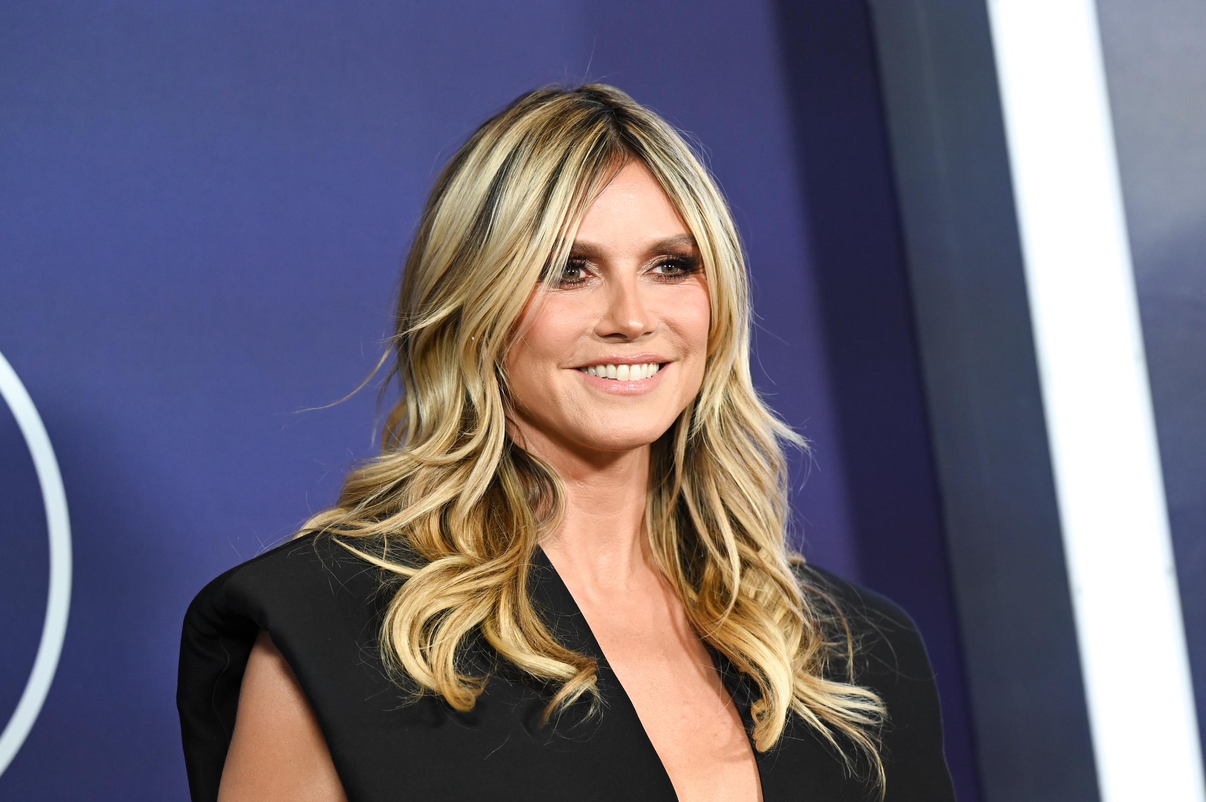 Heidi Klum luce una brillante sonrisa en la alfombra roja de los AMAs, sus suaves rizos enmarcan un look de maquillaje bronceado con ojos ahumados y labios nude que mantienen su glamour equilibrado sin esfuerzo.