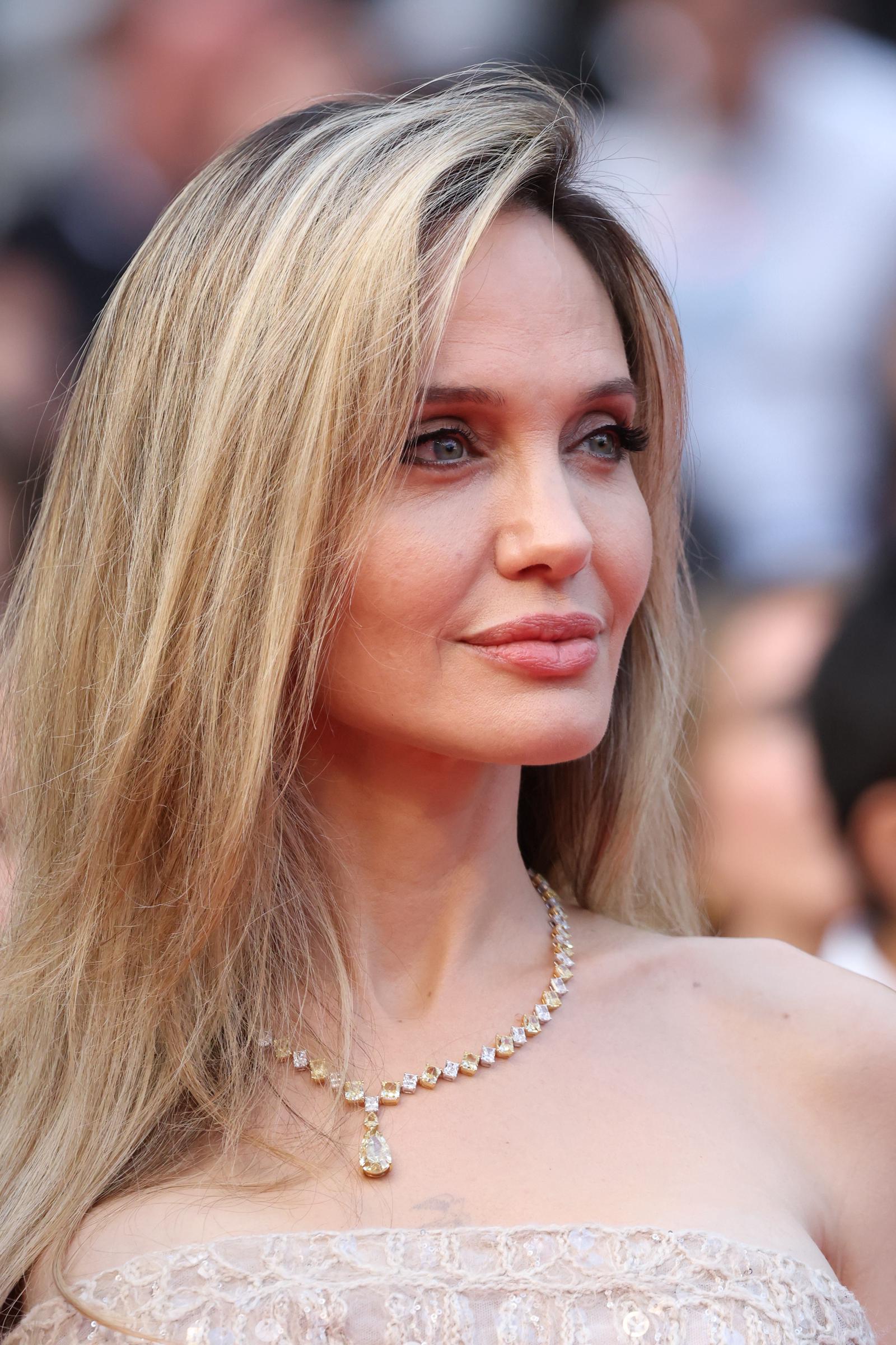 En un primer plano que capta hasta el más mínimo detalle, el suave maquillaje glamuroso y el collar de diamantes de Angelina Jolie brillan bajo las luces de Cannes, resaltando su expresión serena y su elegancia dorada.