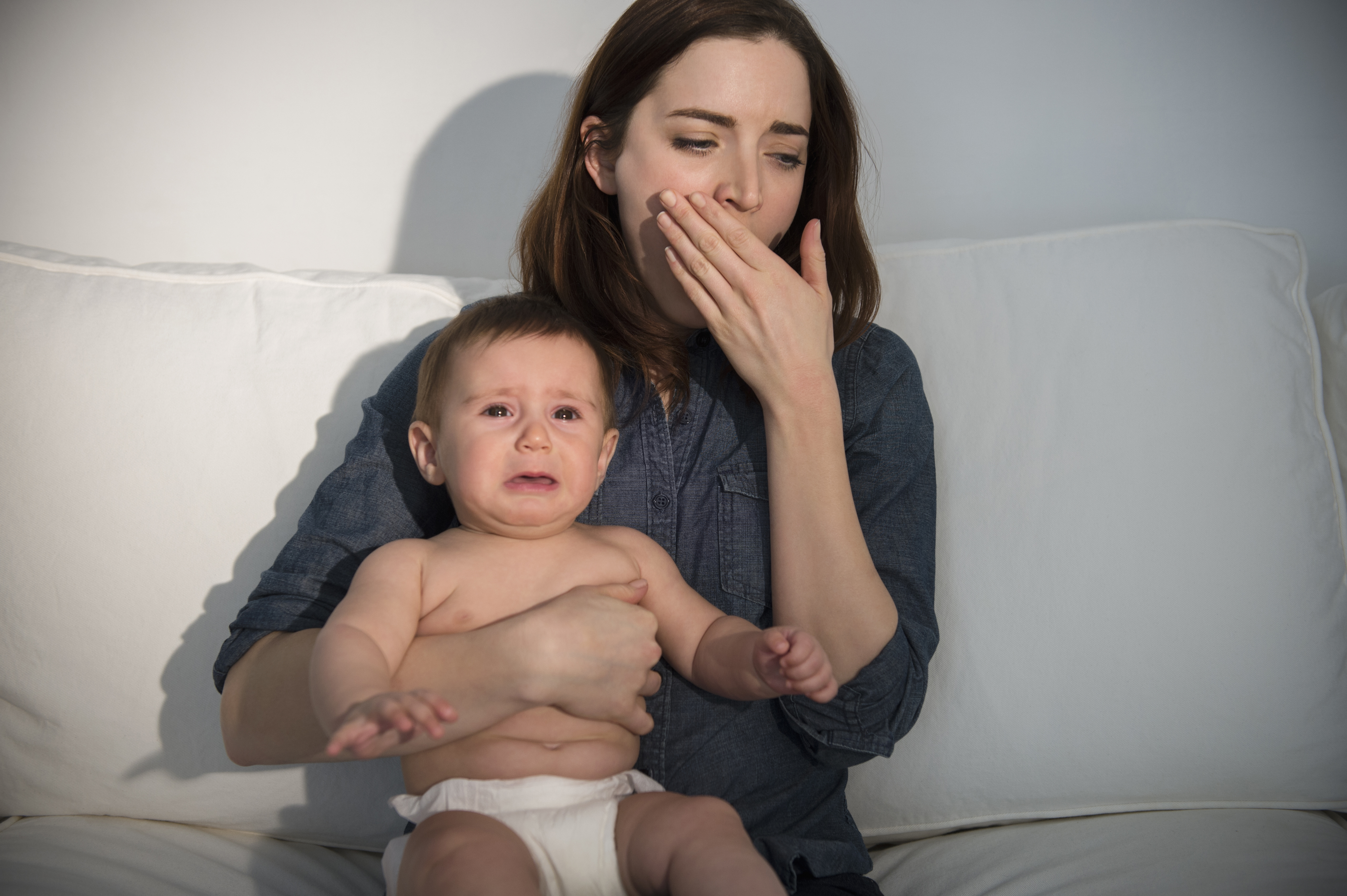 Madre con un bebé llorando bosteza | Foto: Getty Images