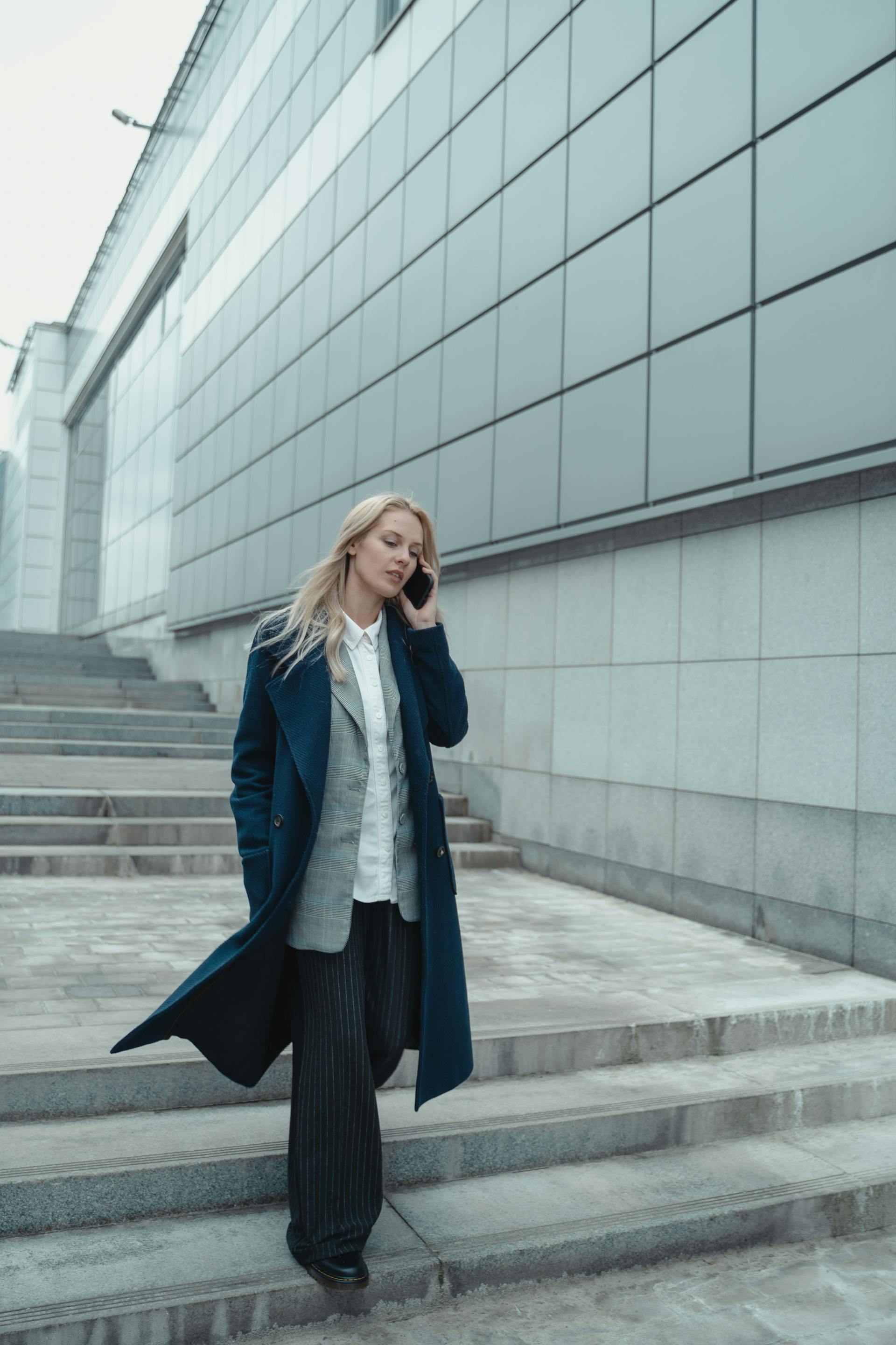 Una mujer hablando por teléfono mientras baja una escalera | Fuente: Pexels