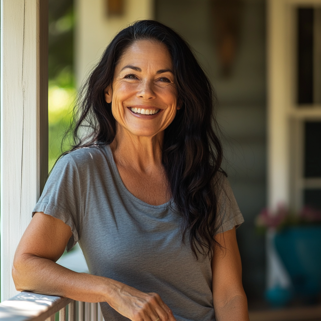 Una donna sorridente sulla veranda di casa sua | Fonte: Midjourney