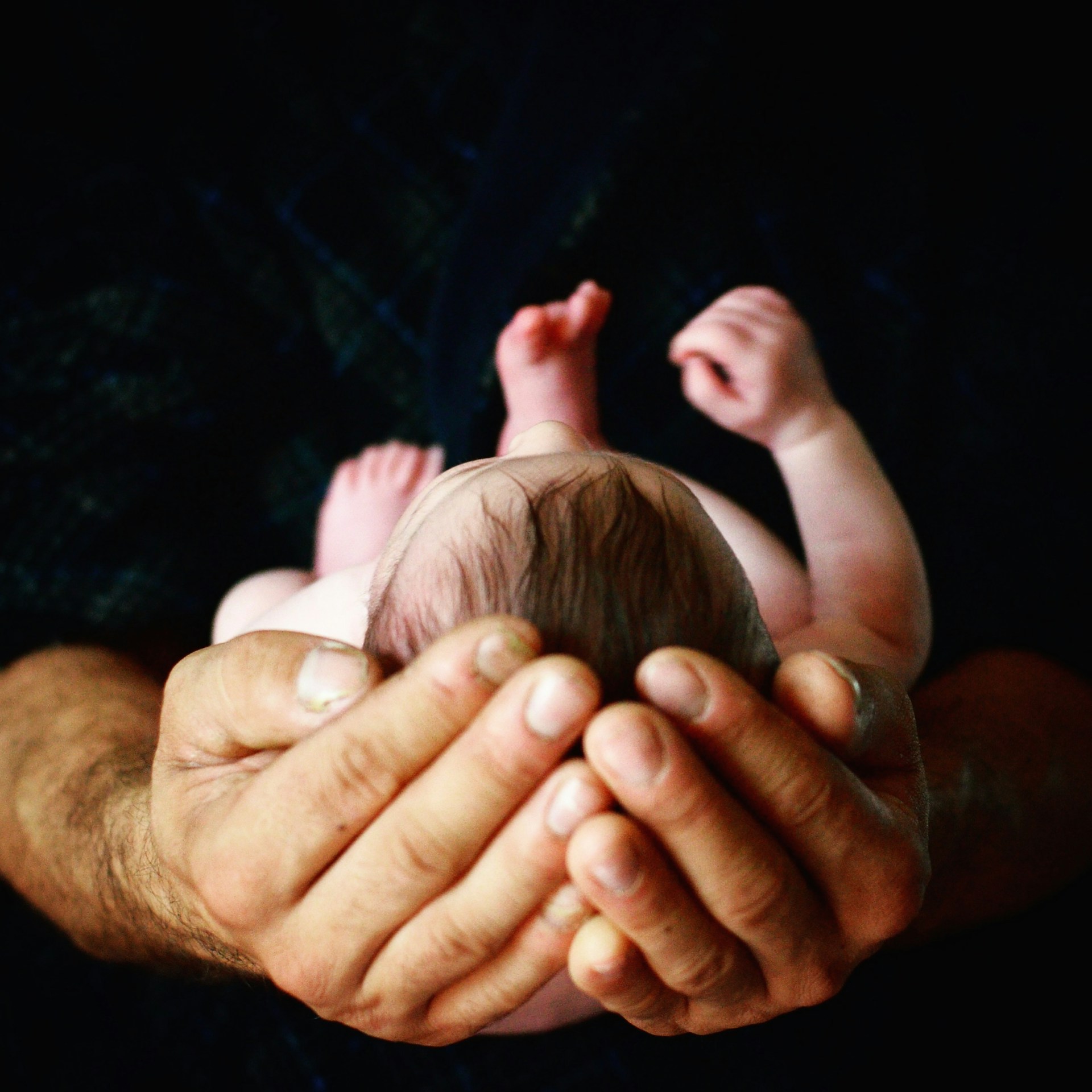 Recorte de un hombre con un bebé recién nacido en brazos | Fuente: Unsplash