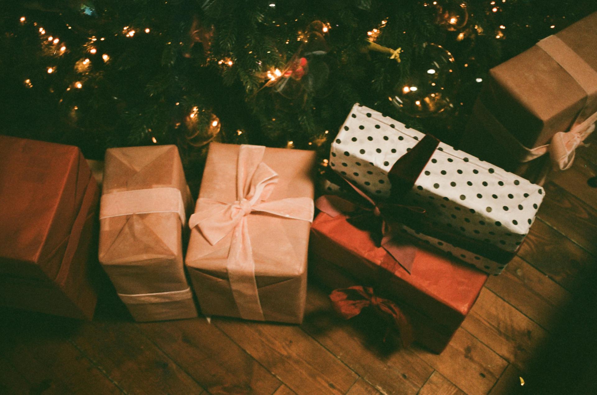 Cajas de regalo variadas en el suelo cerca de un árbol de Navidad | Fuente: Pexels