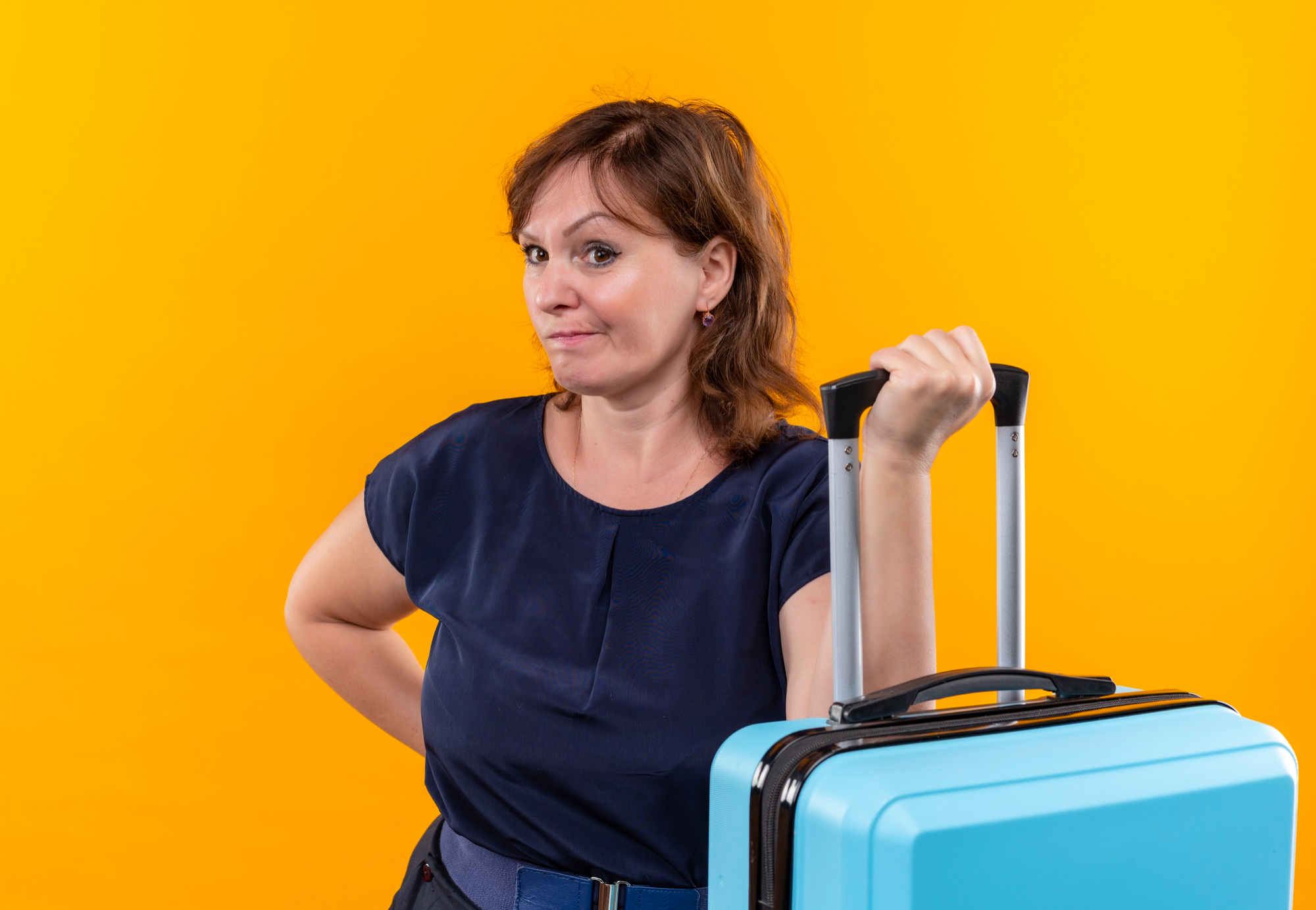 Una mujer de aspecto molesto sujetando un equipaje | Foto: Freepik