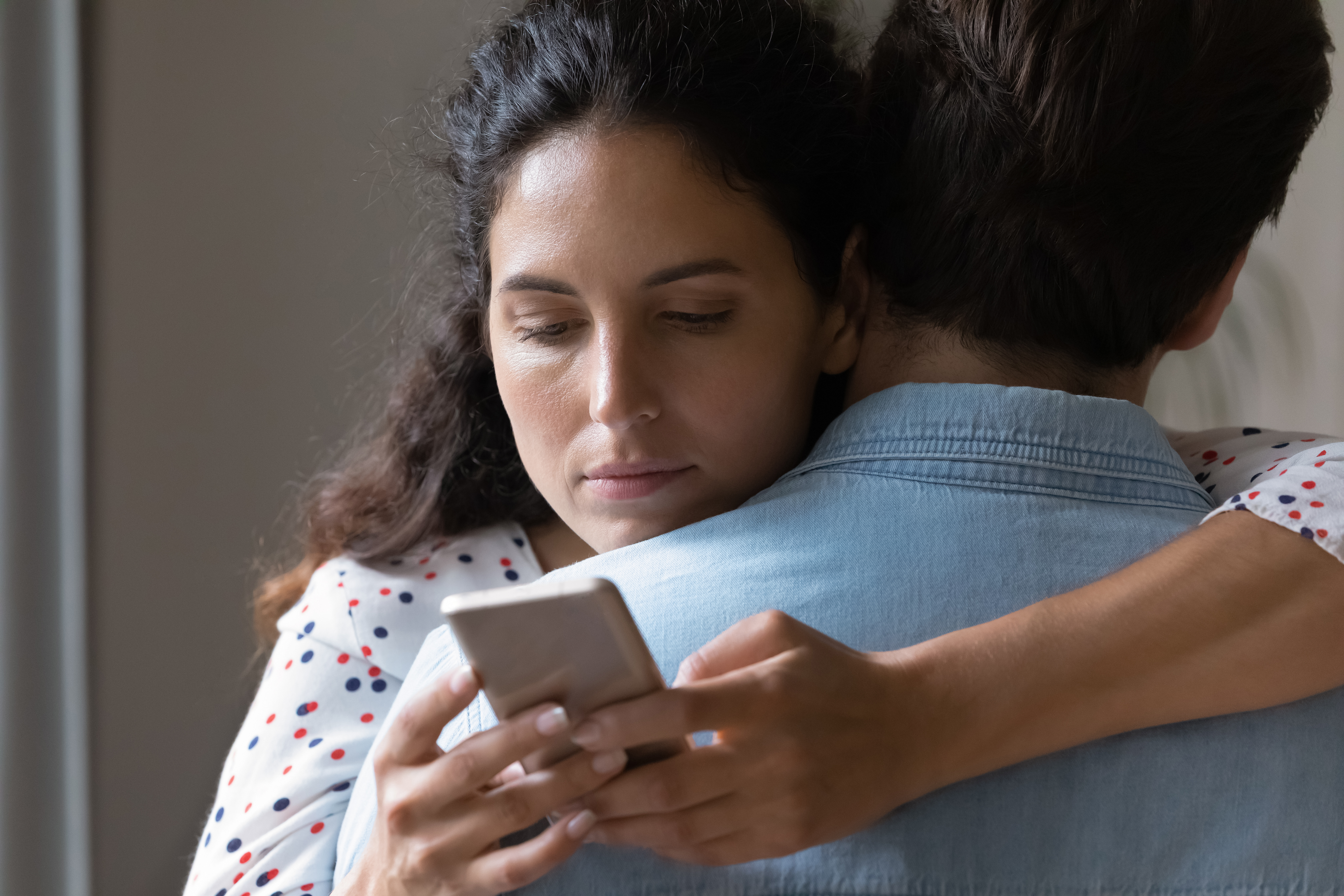 Mujer abraza a alguien y usa el celular | Foto: Getty Images