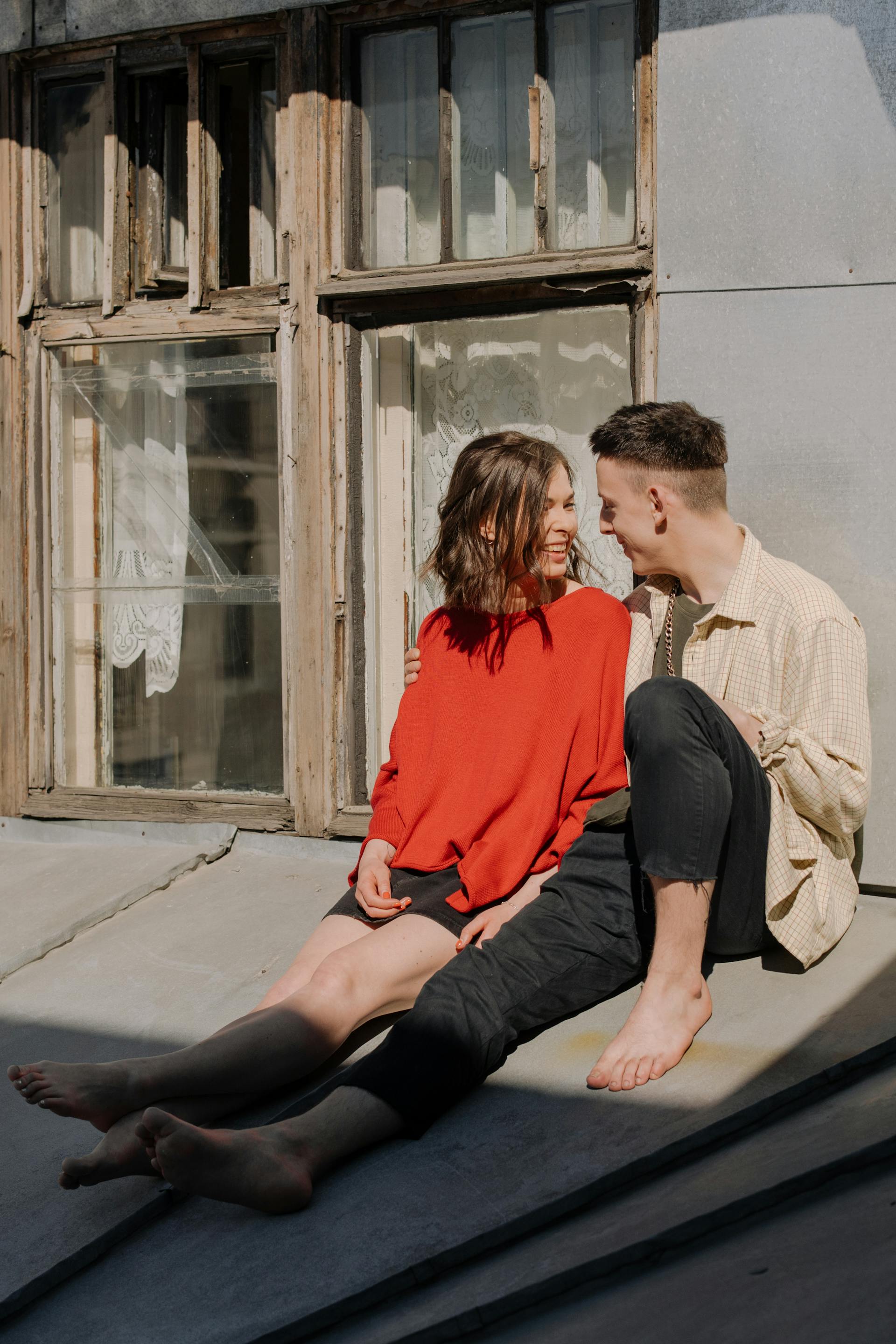 Una pareja ríe sentada frente a un edificio | Fuente: Pexels