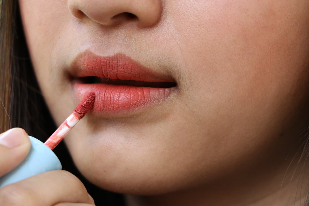 Mujer aplicando lápiz labial mate. | Foto: Shutterstock