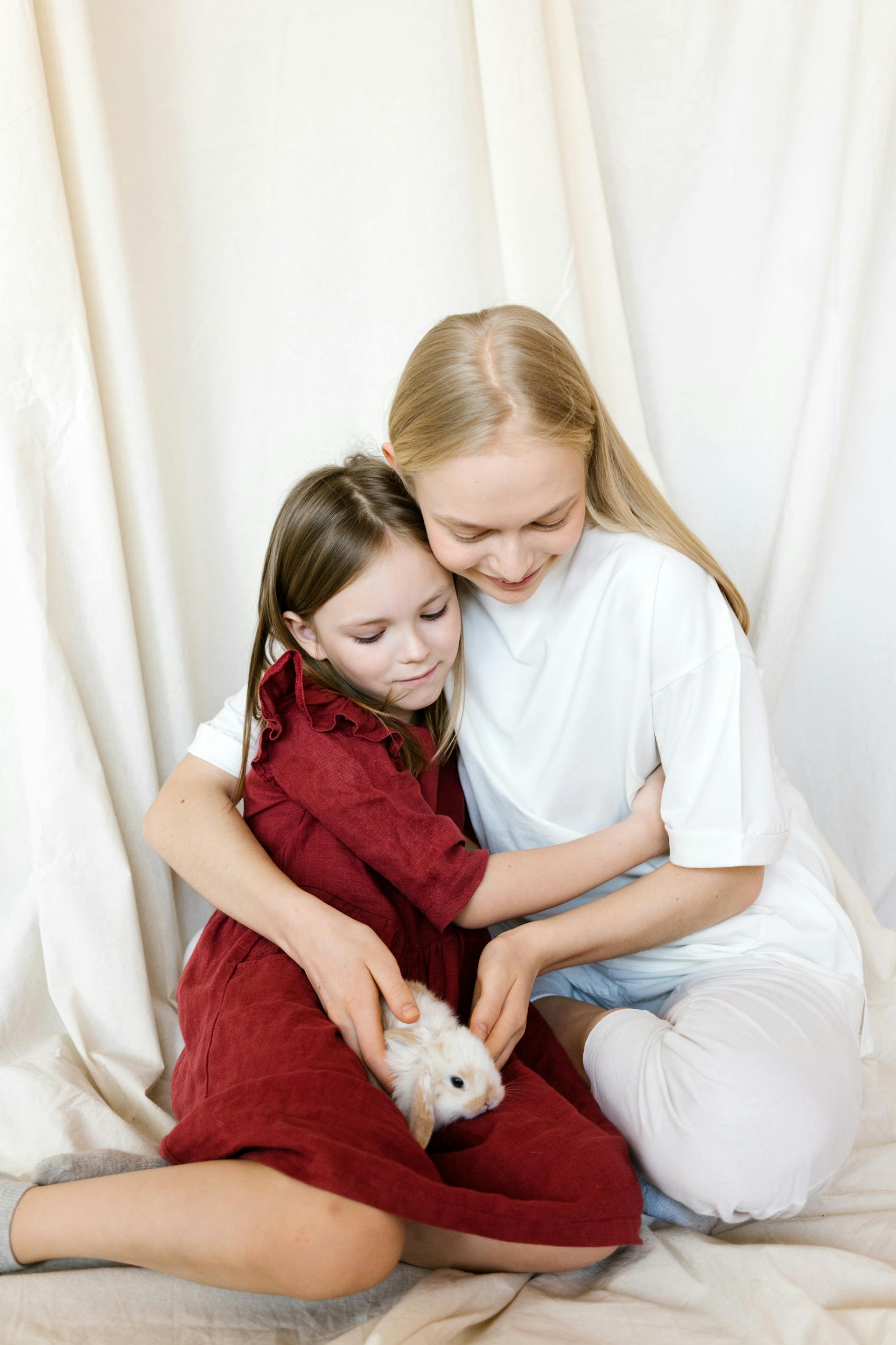 Una niña abrazando a su madre mientras mira un conejo | Fuente: Pexels