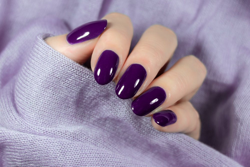 Mano de mujer con esmalte de uñas violeta. | Foto: Shutterstock