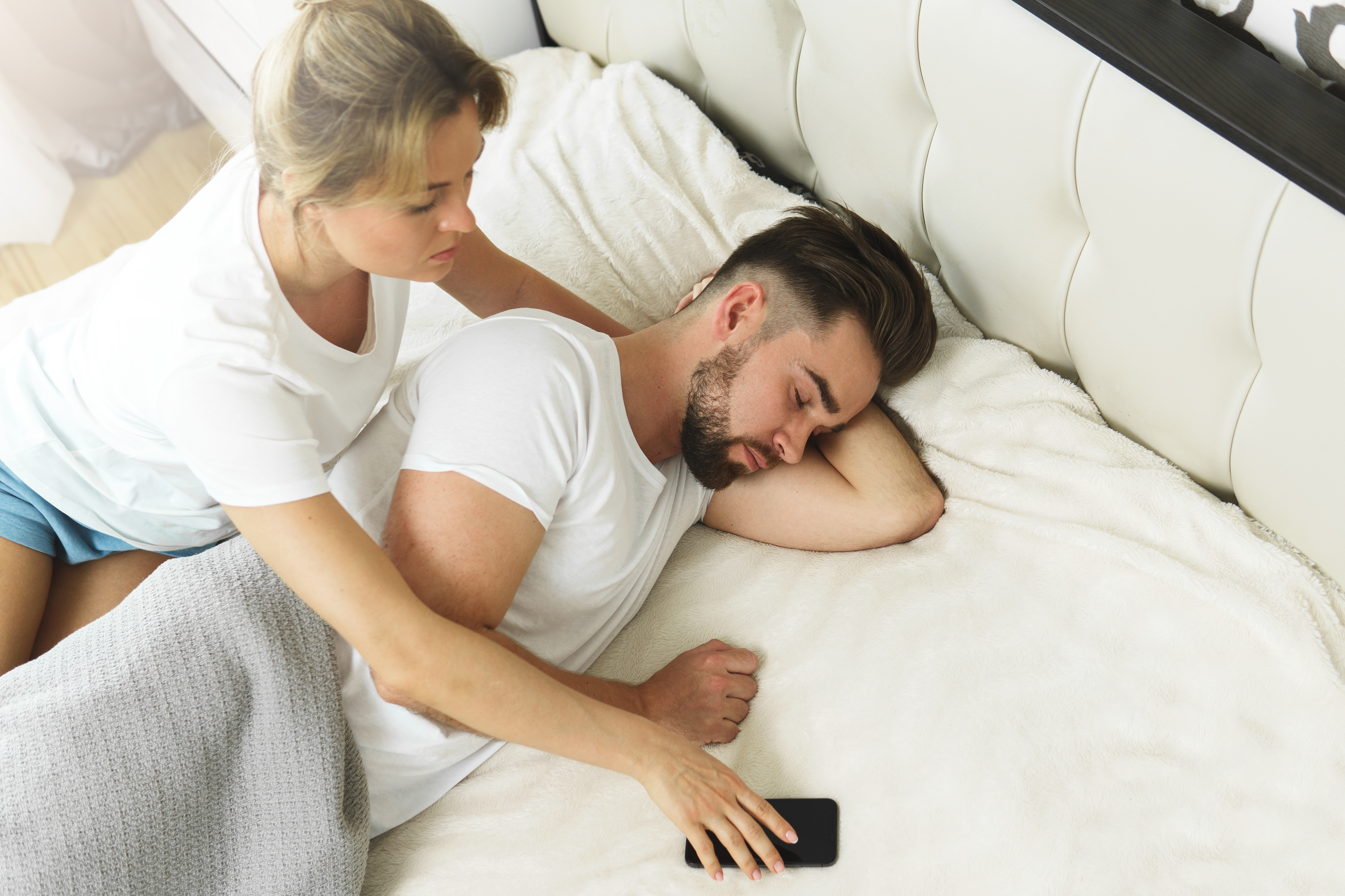 Mujer toma el teléfono de su pareja mientras duerme | Fuente: Shutterstock