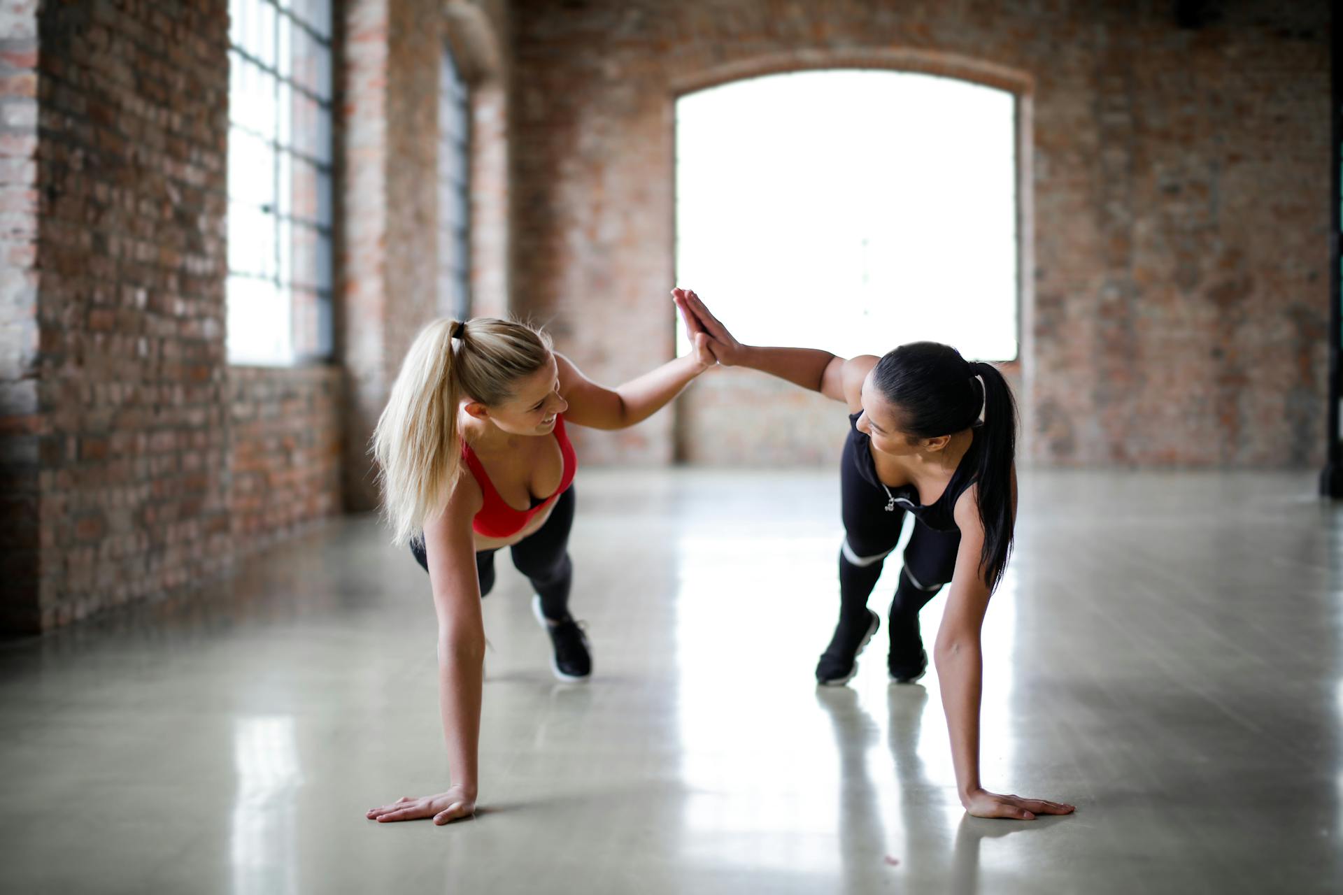 Dos mujeres chocando manos mientras hacen ejercicio | Foto: Pexels