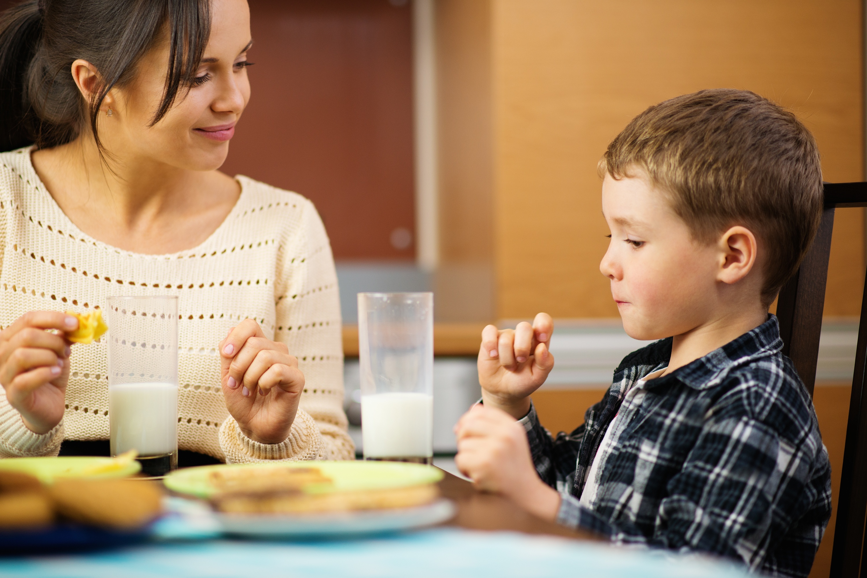 Joven madre feliz y su hijo comiendo. | Fuente: Shutterstock