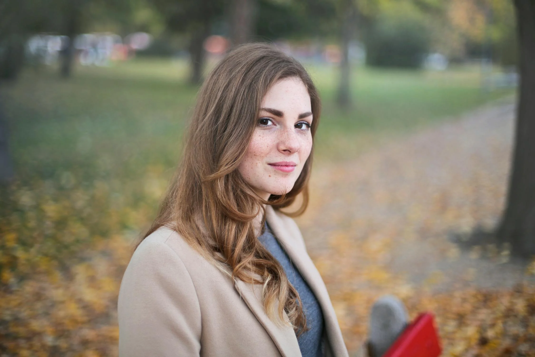 Una joven sonriente sentada en un parque | Fuente: Pexels