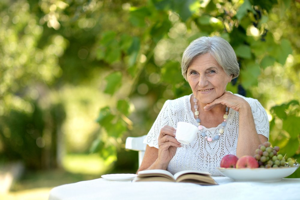 Retrato de una bella mujer de mayor edad al aire libre en una mesa. Fuente: Shutterstock
