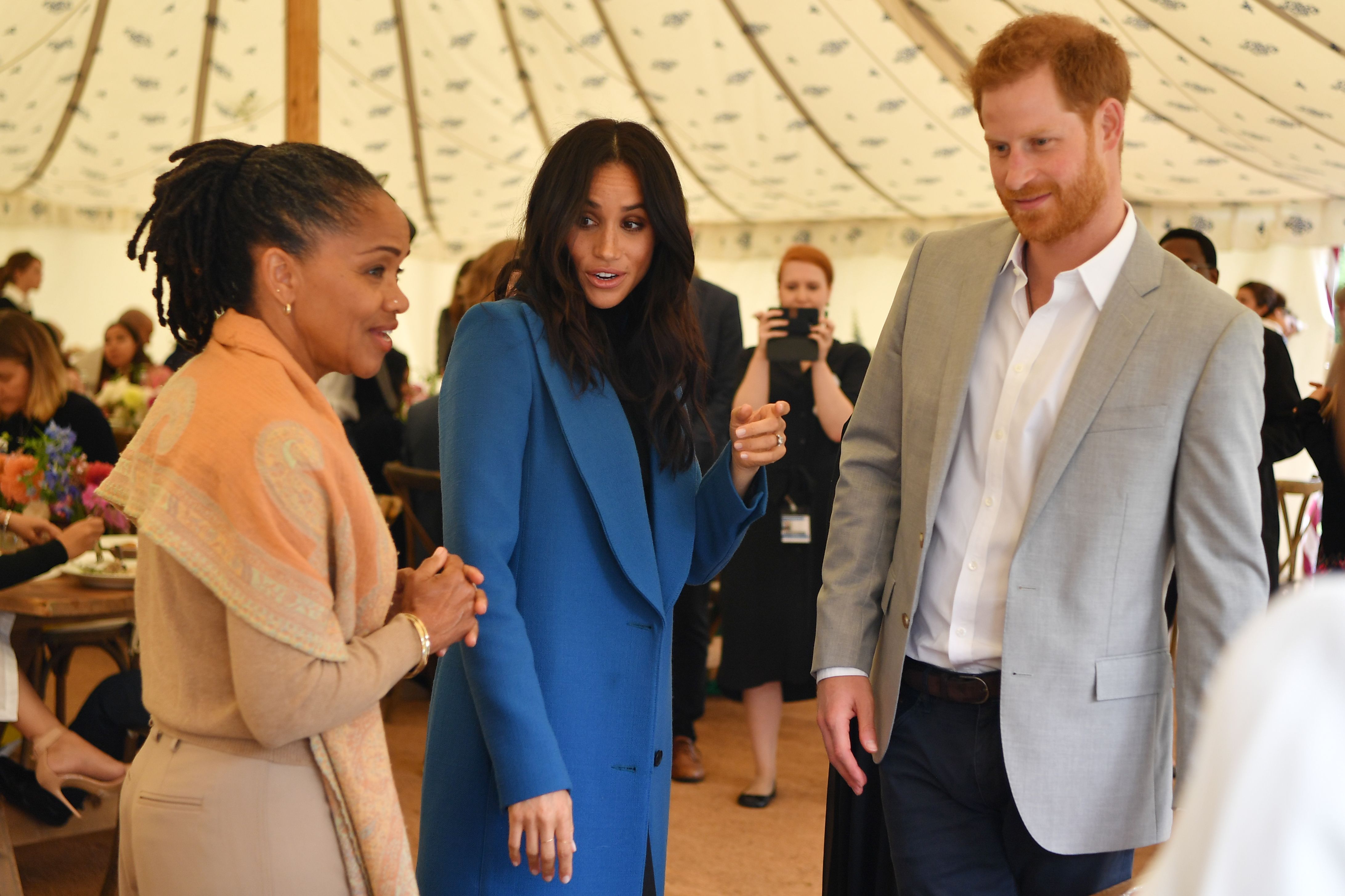 Doria Ragland, la duquesa Meghan y el príncipe Harry en la presentación de un libro de cocina con recetas de un grupo de mujeres afectadas por el incendio de la Torre Grenfell en el Palacio de Kensington, en Londres, el 20 de septiembre de 2018. | Foto: Getty Images