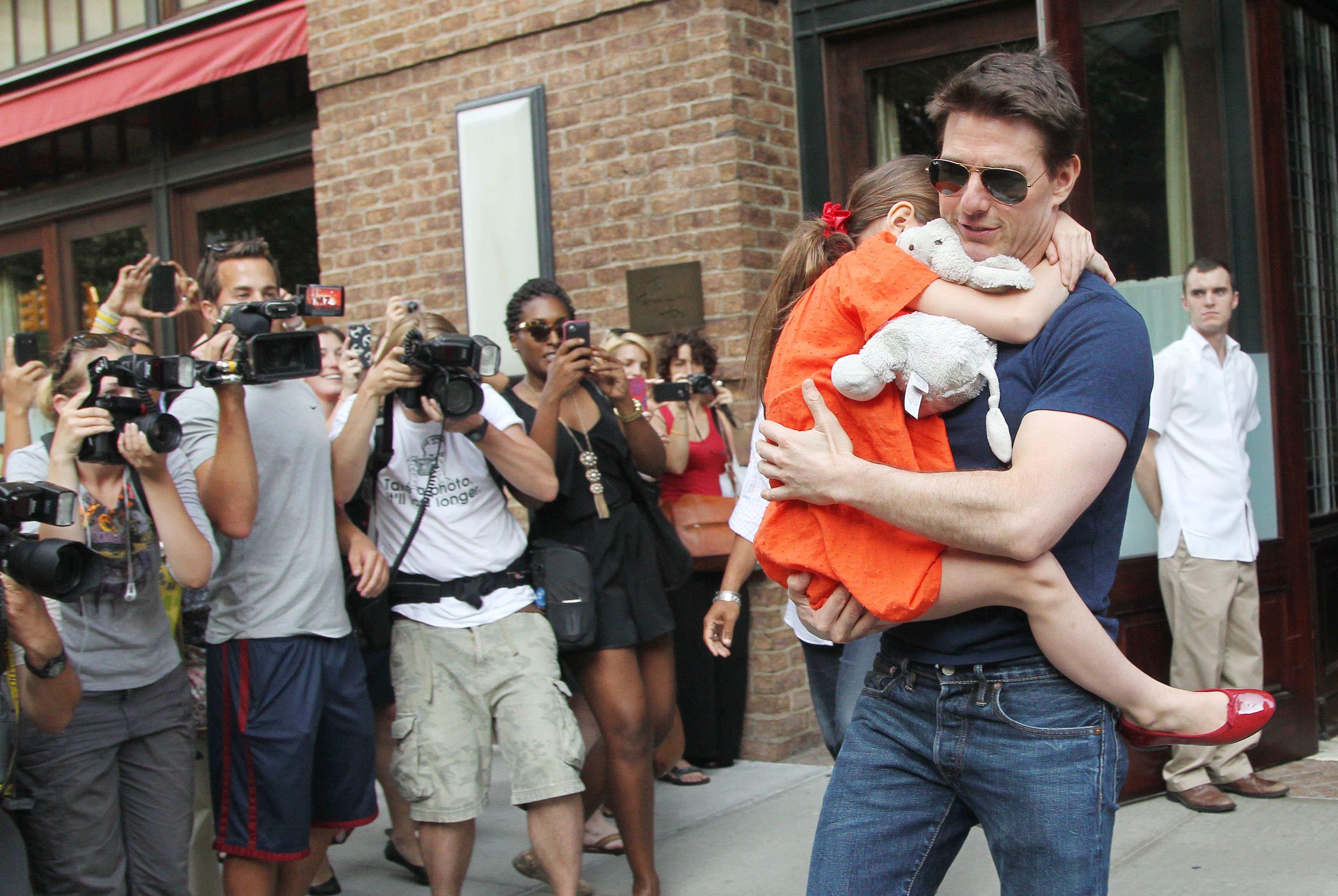 Tom Cruise carga a Suri cuando salen de un edificio en la ciudad de Nueva York en 2012. | Foto: Getty Images