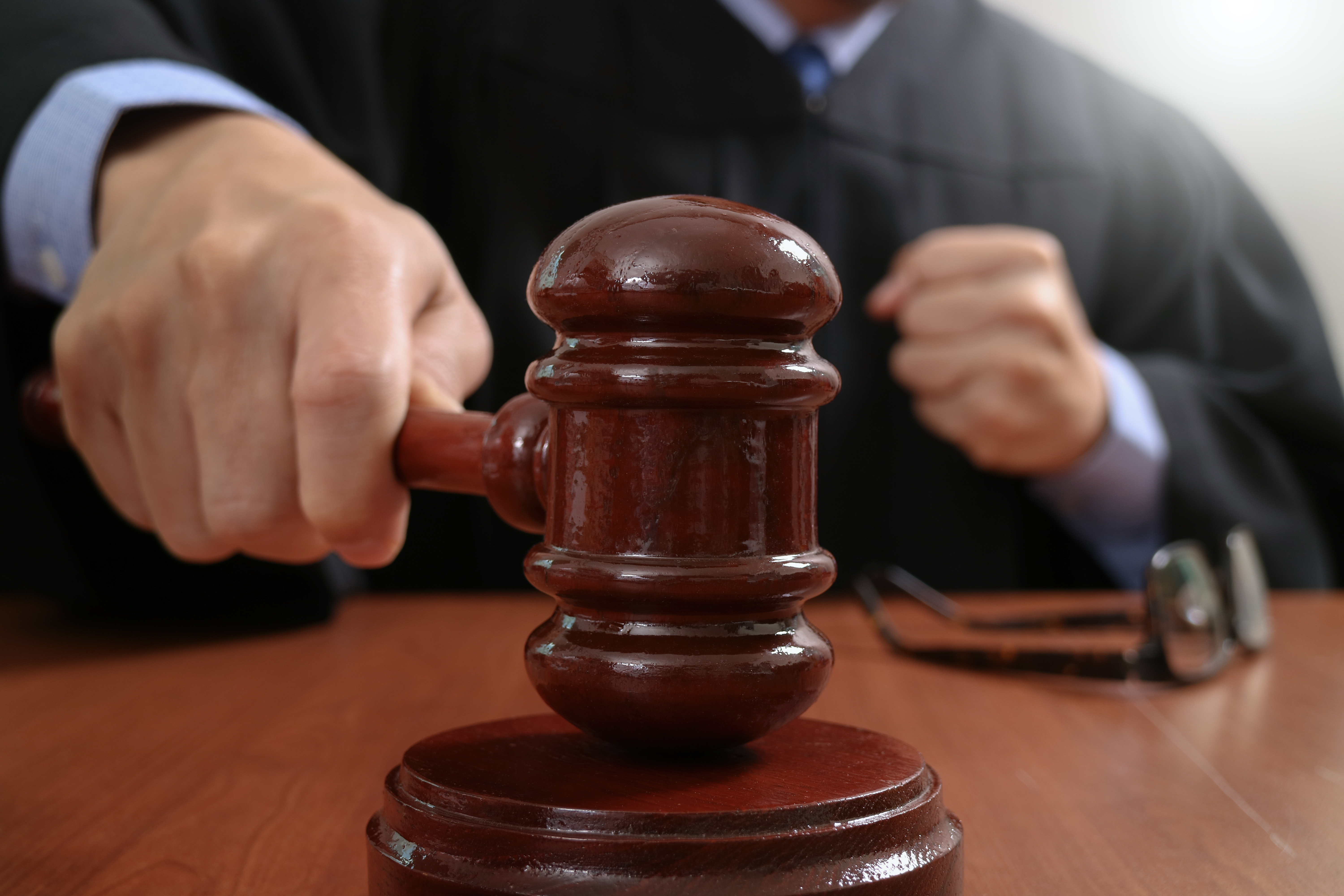 Un hombre sostiene un mazo para golpear el bloque sonoro en la sala de un tribunal | Foto: Shutterstock