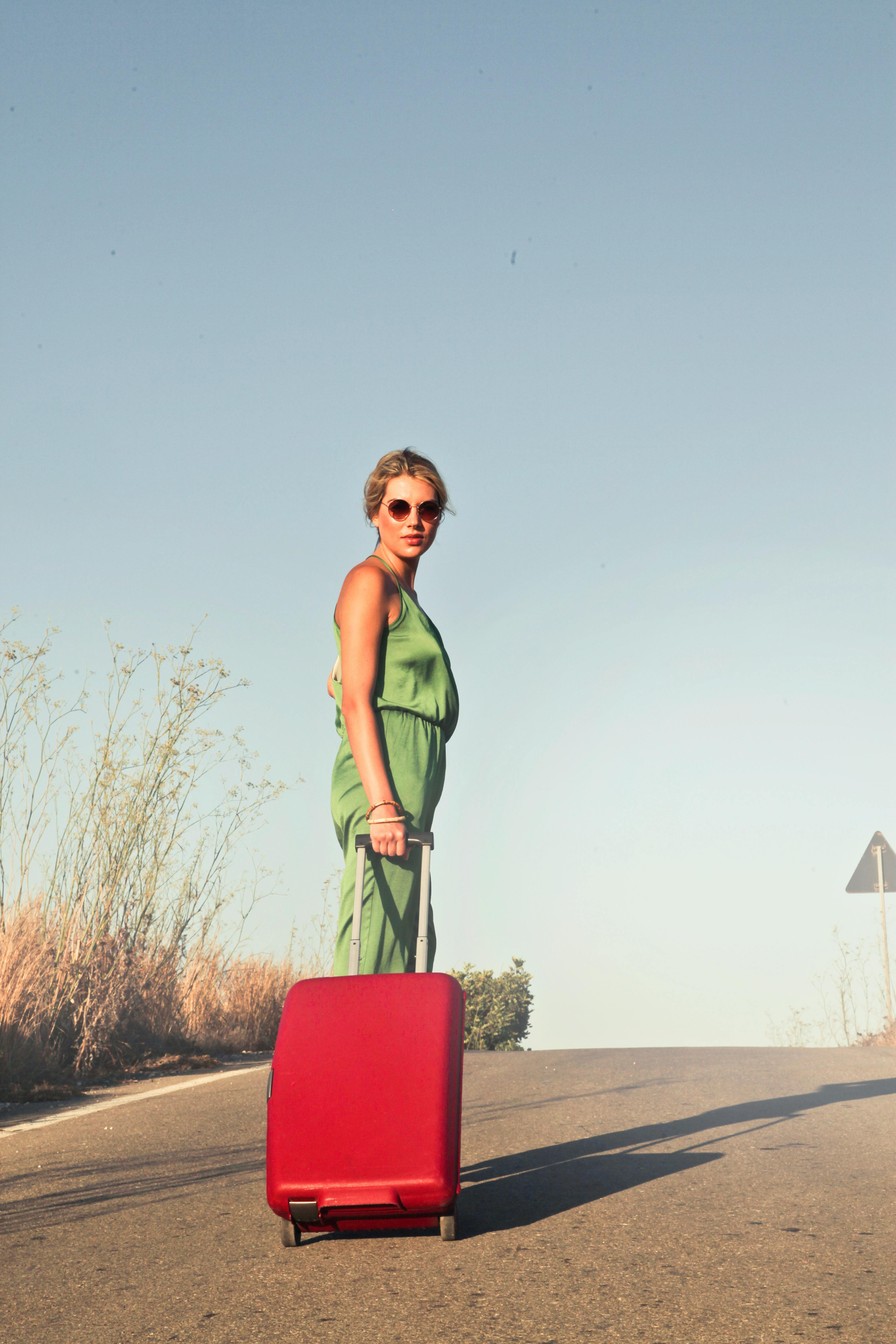 Una mujer caminando con una maleta roja | Fuente: Pexels