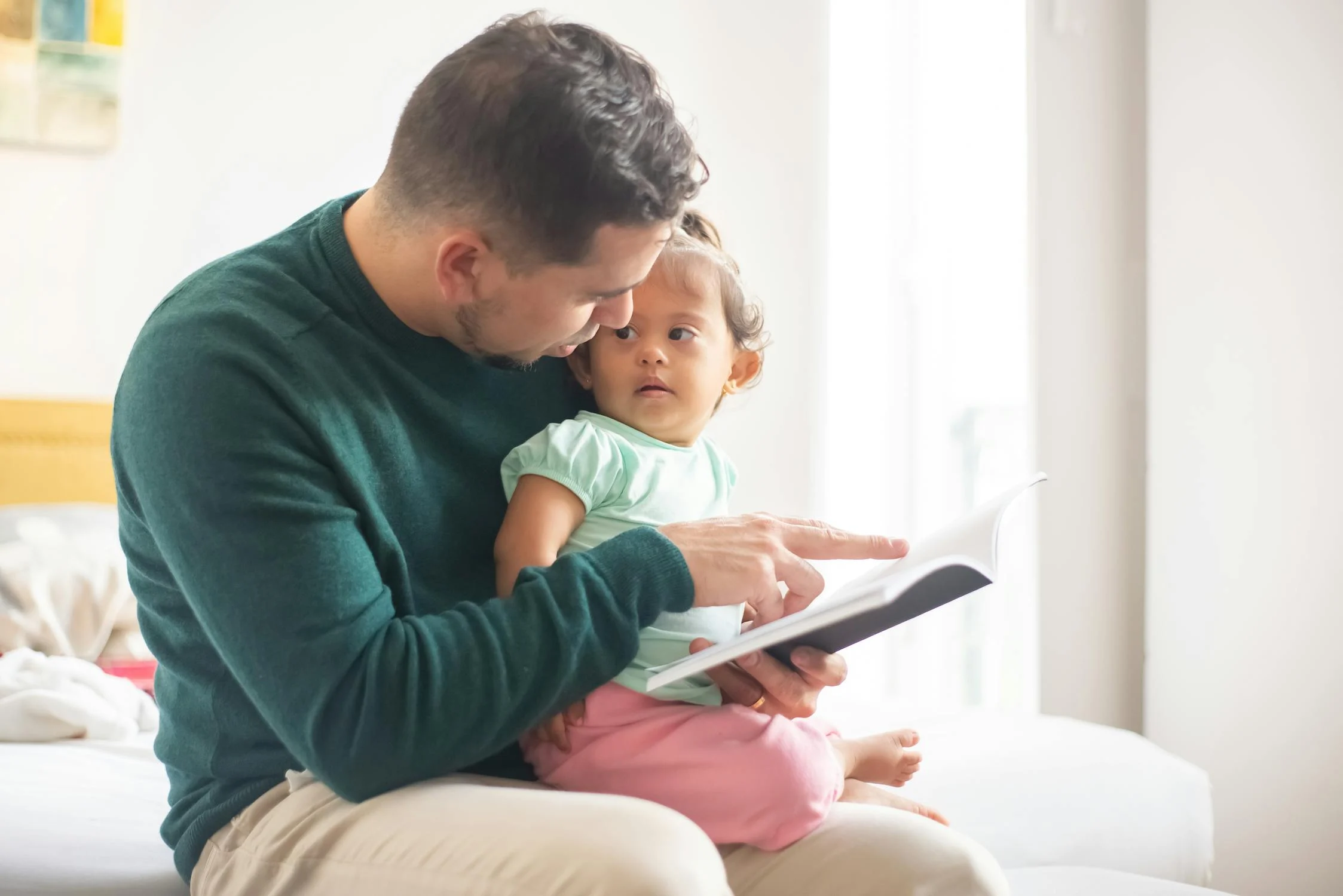 Un hombre leyendo un libro a su hija | Fuente: Pexels