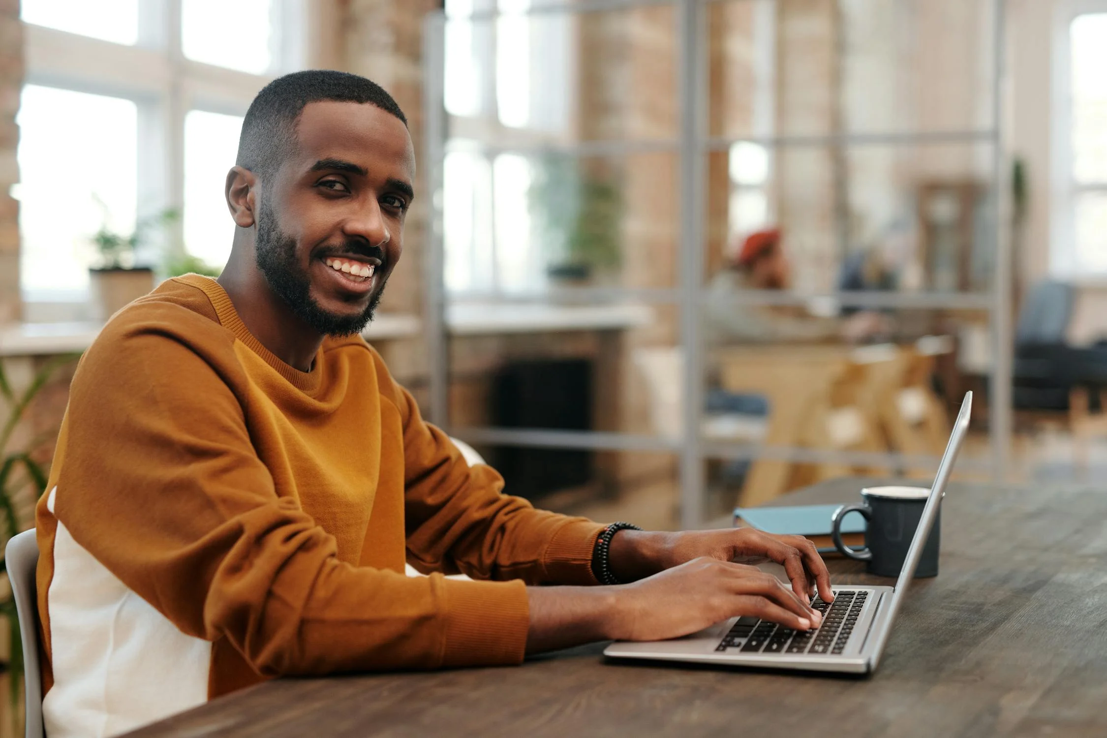 Un hombre sonriente con un portátil | Fuente: Pexels