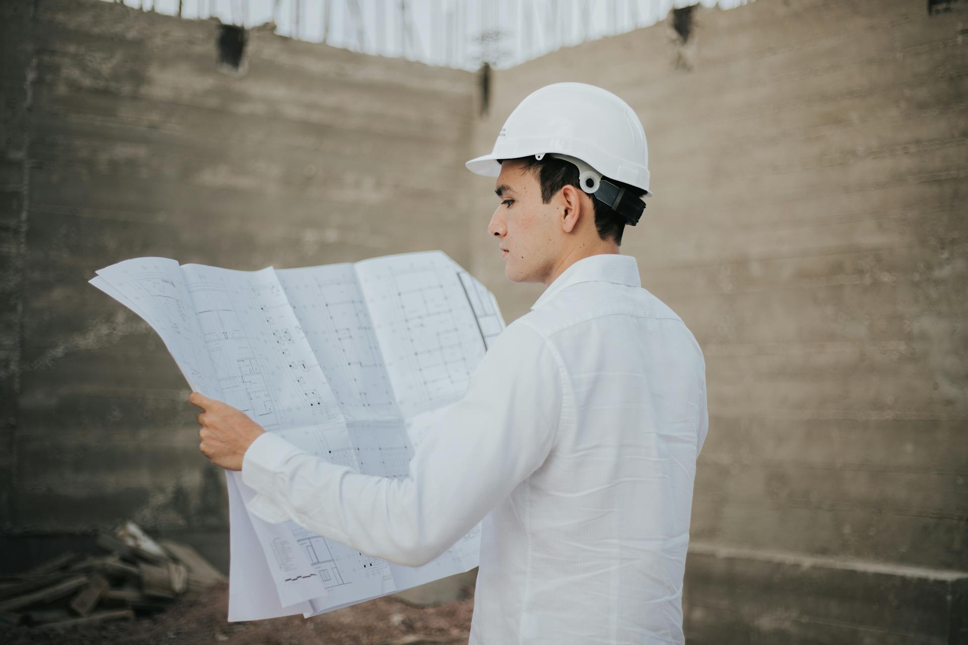 Un arquitecto examinando el trazado de un plano | Fuente: Pexels