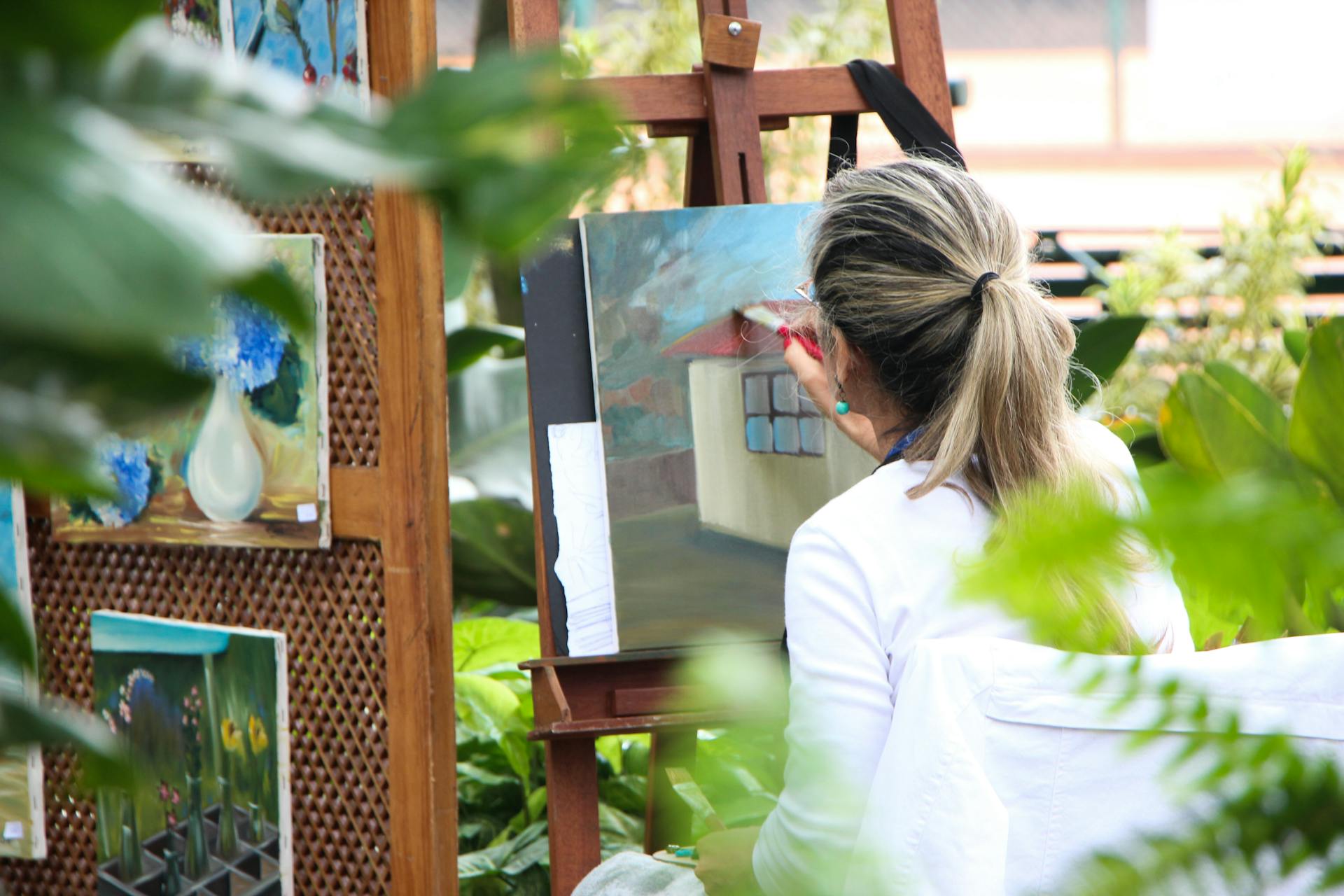 Vista trasera de una mujer pintando un cuadro en el jardín | Fuente: Pexels