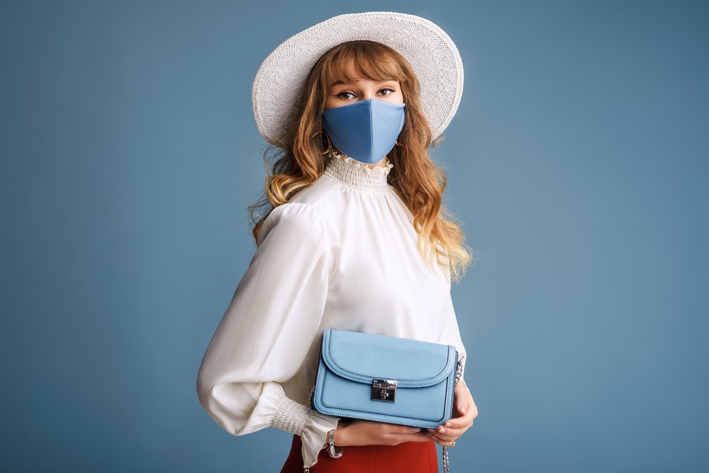 Mujer usando tapaboca de color azul, combinado con su bolso. | Foto: Shutterstock