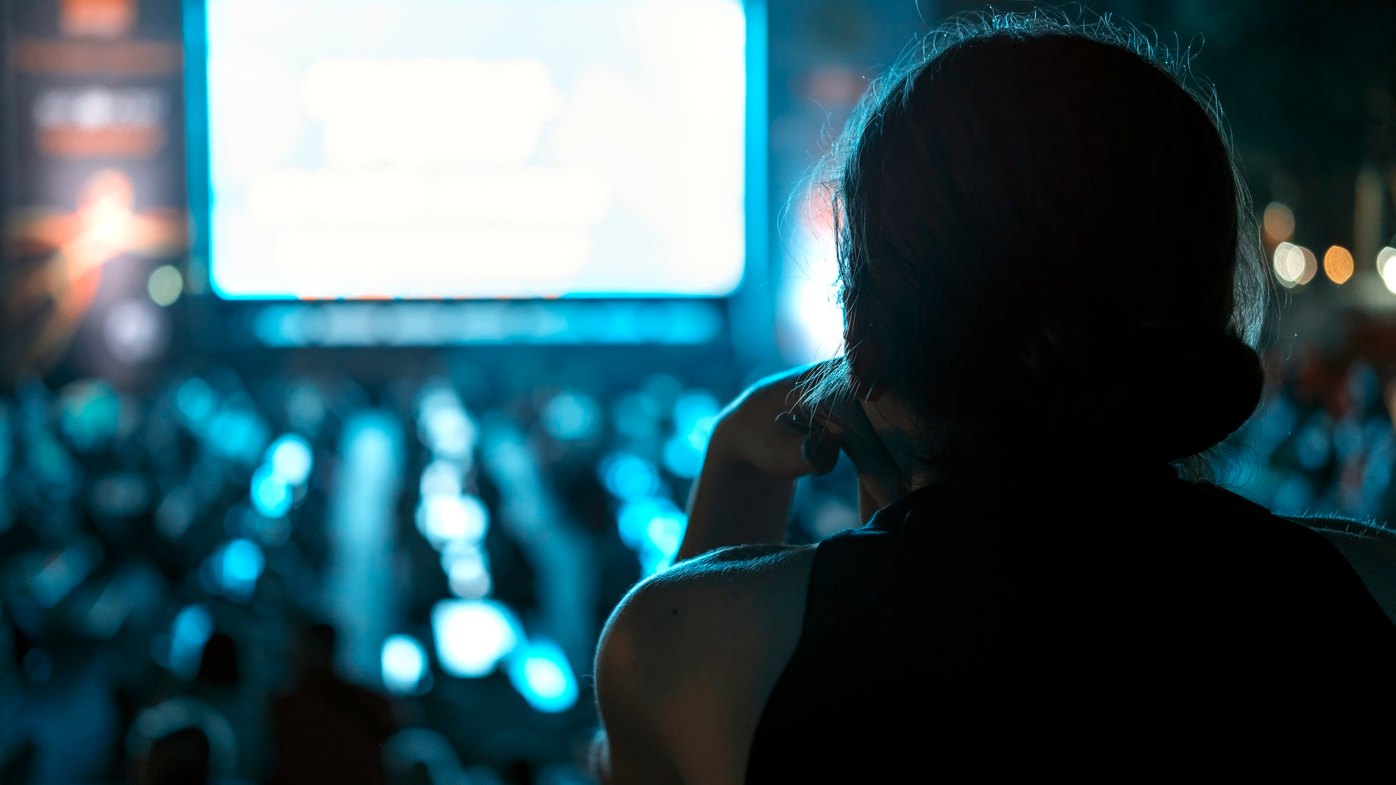 Una mujer observa a la gente que mira algo en una pantalla en un evento | Fuente: Freepik