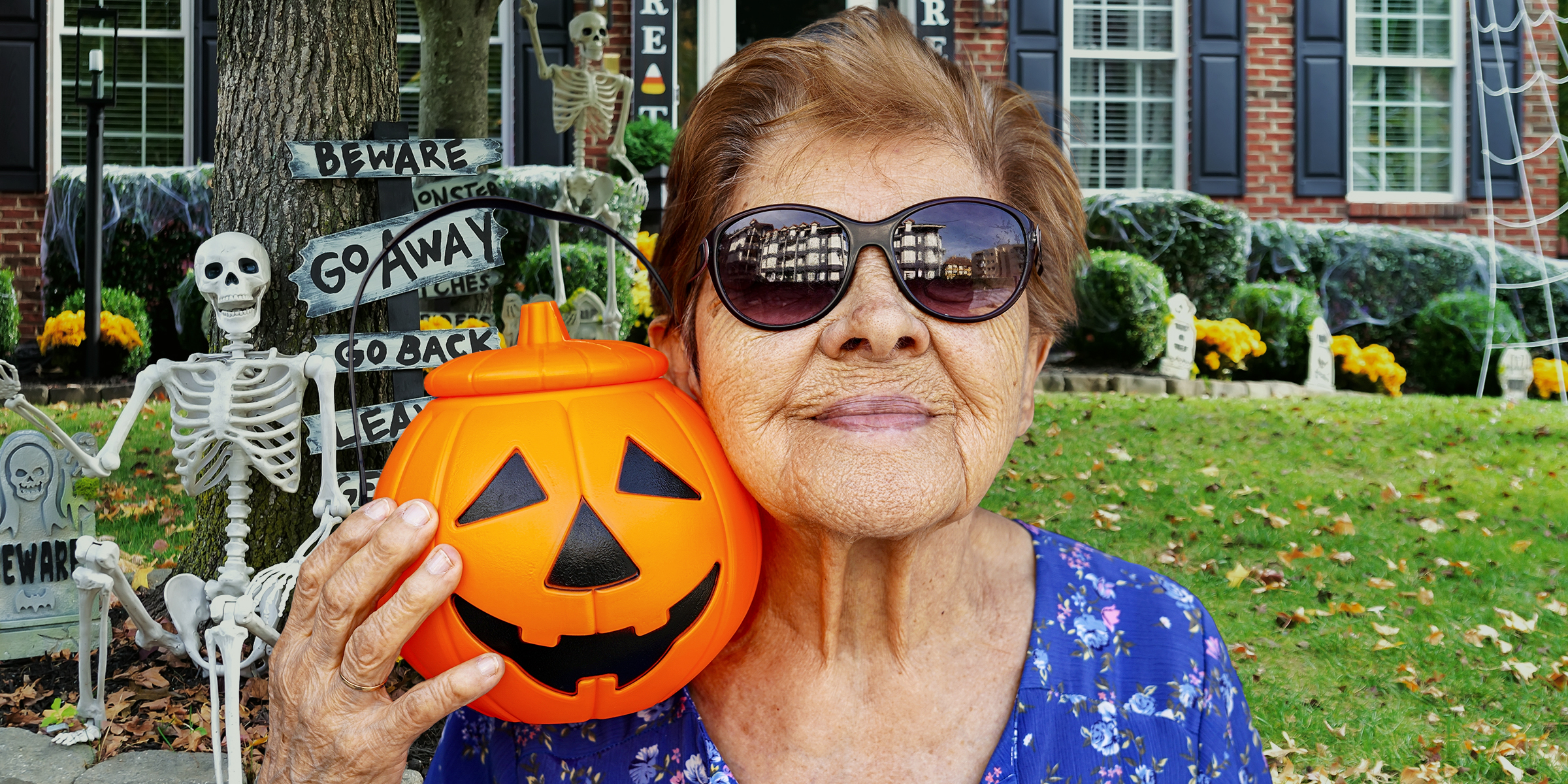 Una mujer mayor sujetando una linterna Jack-o'-lantern | Fuente: Shutterstock