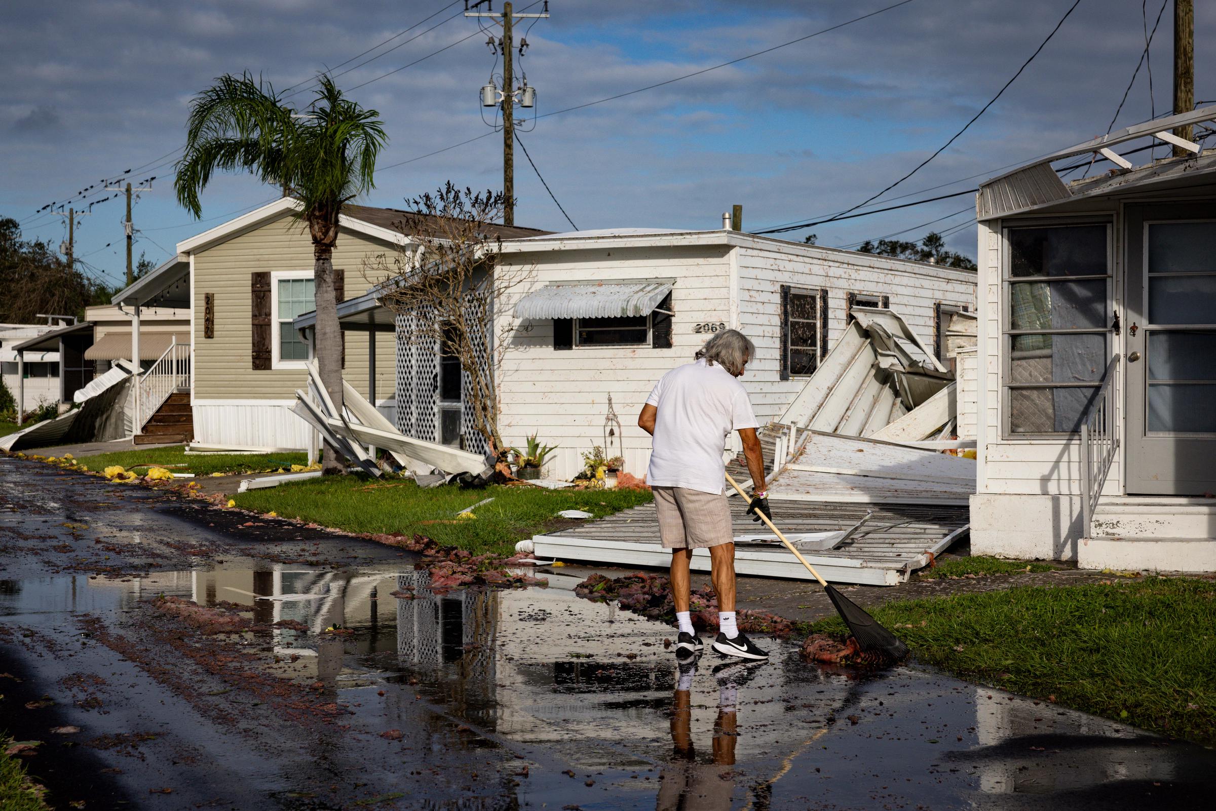 Un residente de Sarasota, Florida, limpia la fachada de su casa móvil tras la llegada a tierra del huracán Milton el 10 de octubre de 2024 | Fuente: Getty Images