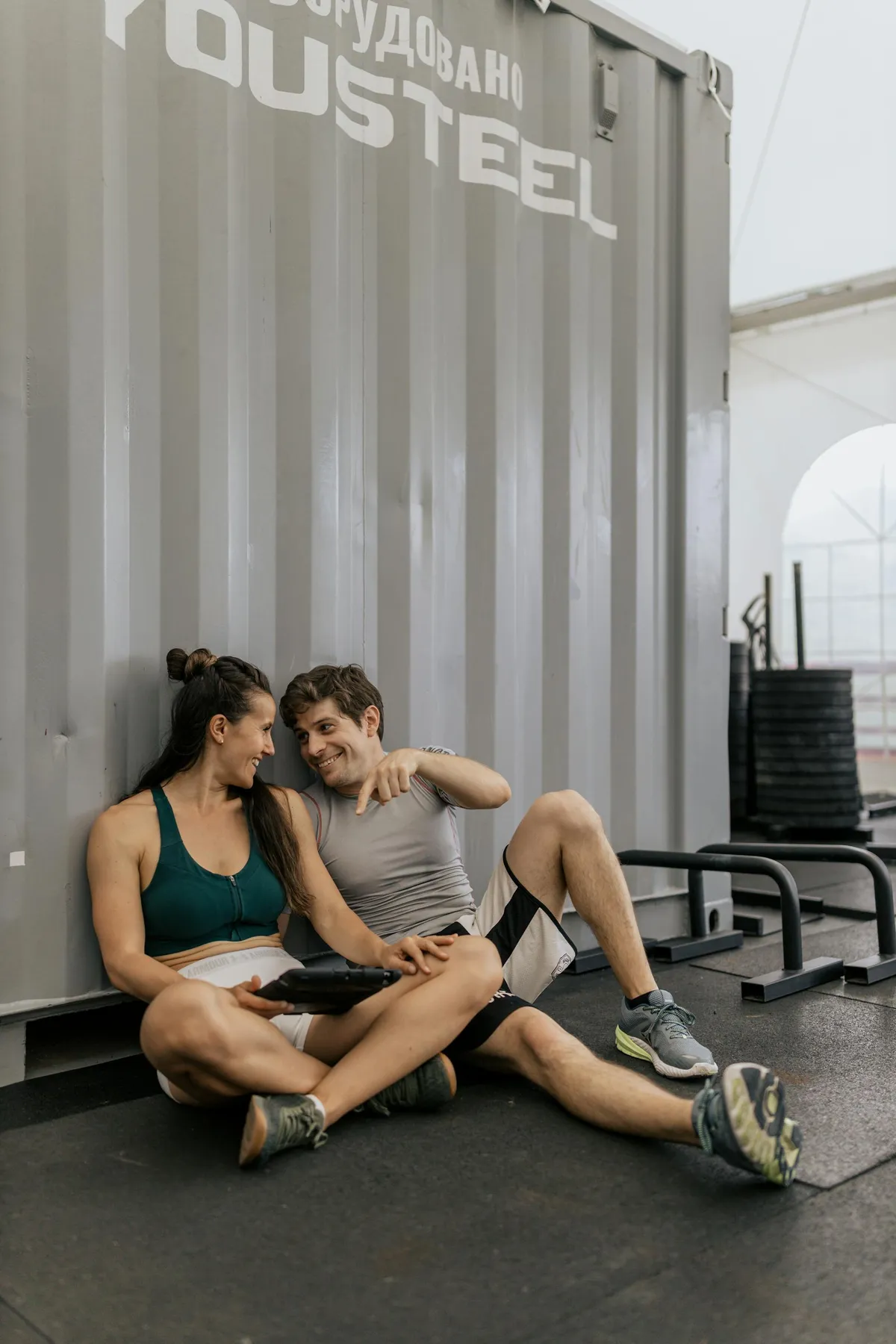 Una pareja con ropa deportiva sentada en el suelo y charlando | Foto: Pexels