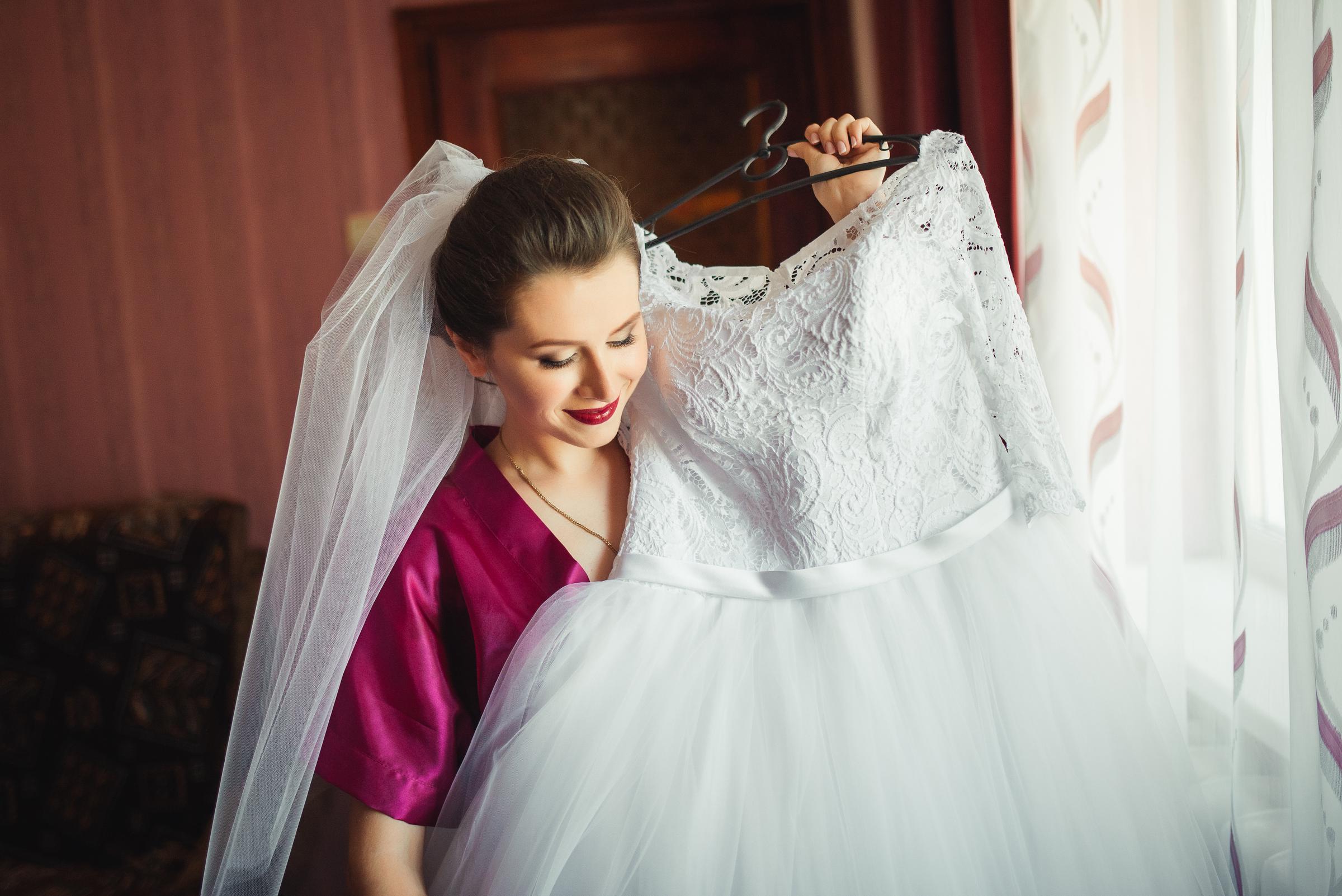 Una mujer alegre sujetando un vestido de novia | Fuente: Freepik