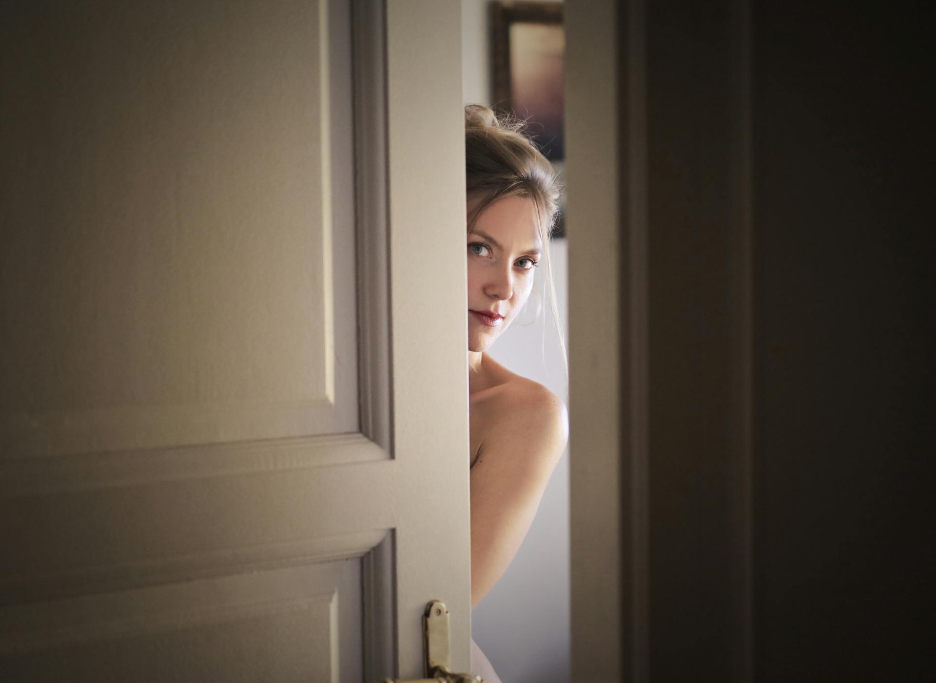 Una mujer asomándose por detrás de la puerta | Fuente: Pexels