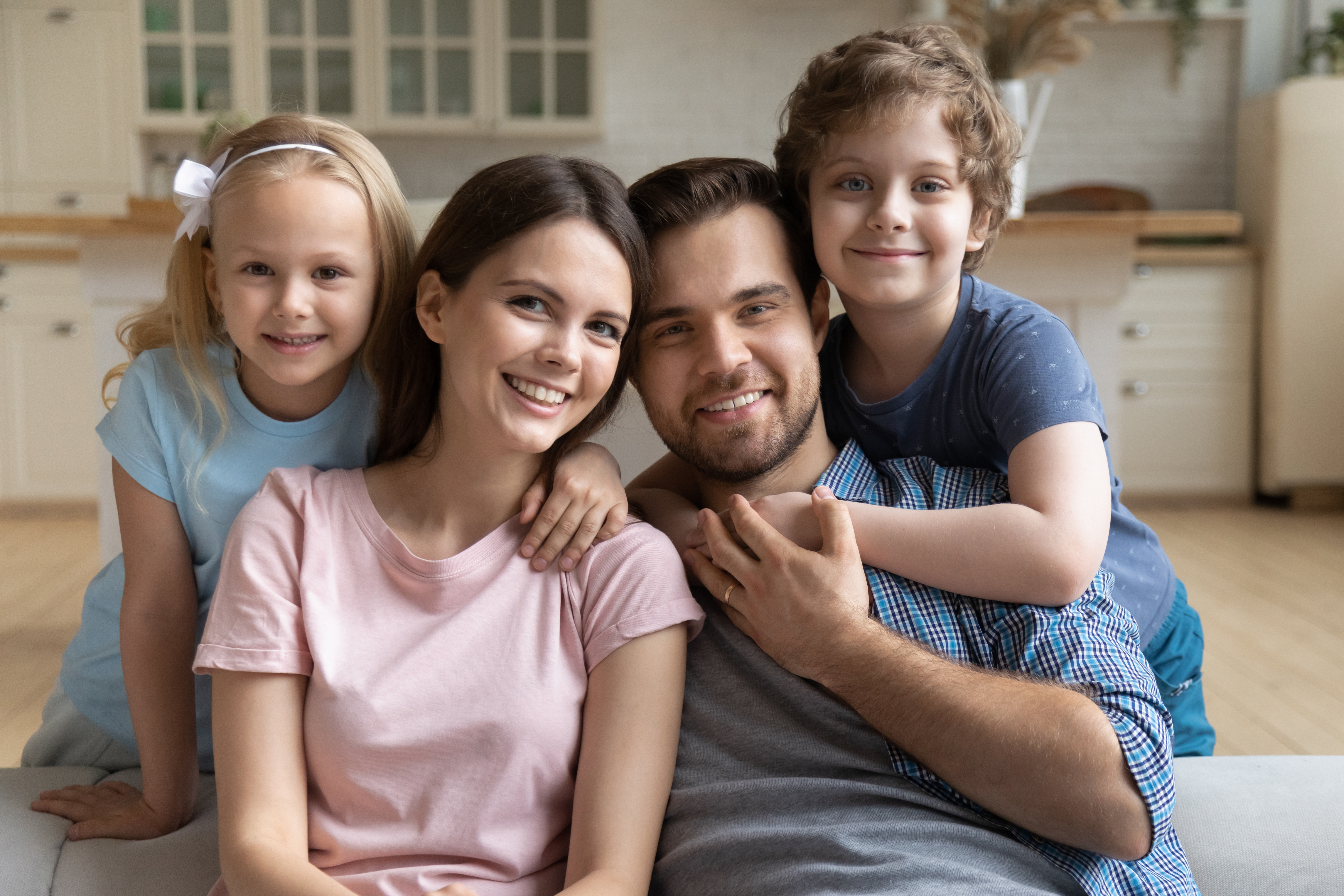 Una pareja abrazando a sus hijos pequeños en casa | Fuente: Shutterstock