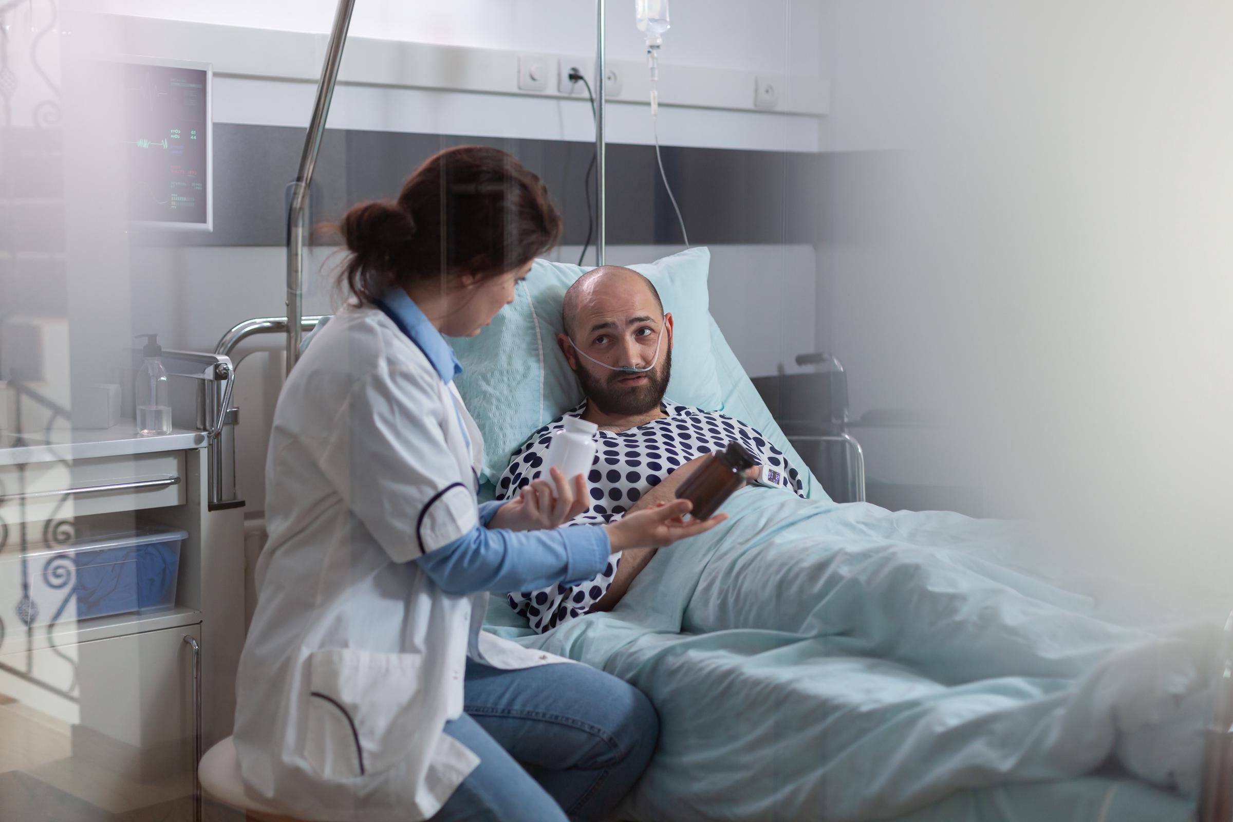 Un hombre enfermo con una mascarilla de oxígeno descansando en la cama durante una revisión médica | Fuente: Magnific