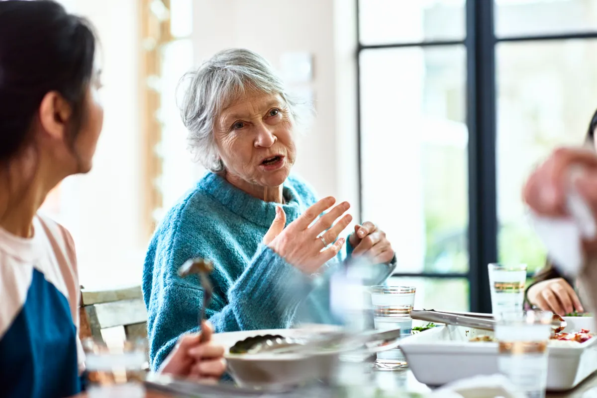 Una abuela contando historias en la mesa | Fuente: Getty Images